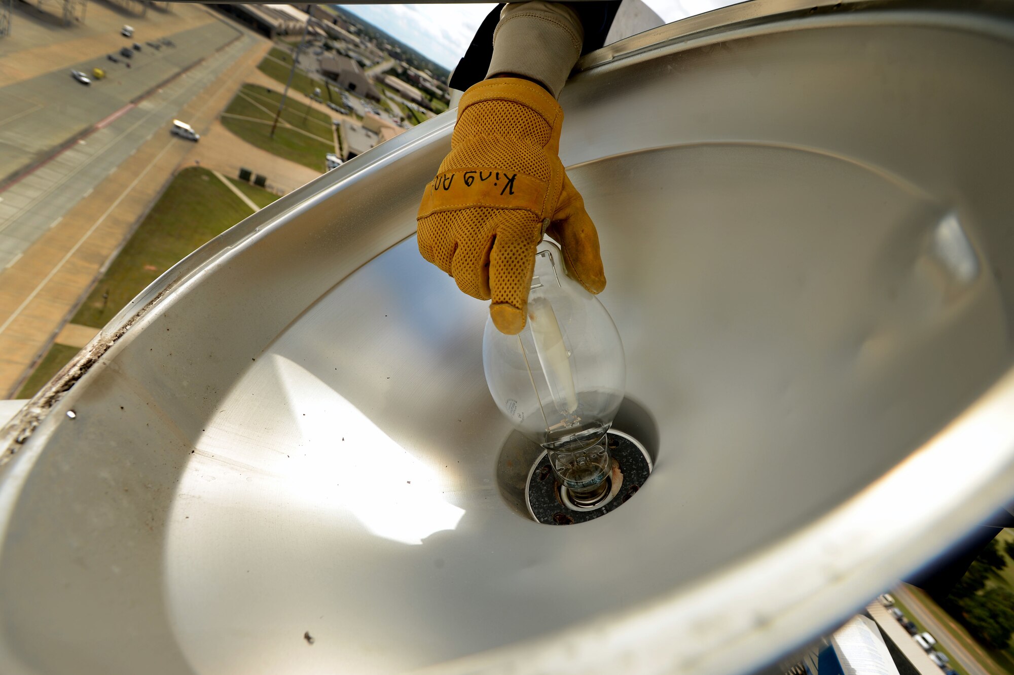 An Airman assigned to the 20th Civil Engineer Squadron reaches out to install a light bulb on a ramp light along the flightline at Shaw Air Force Base, S.C., Oct. 16, 2014. Each of the approximately 200 light bulbs are 875 watts to ensure adequate lighting for the security of the flightline. (U.S. Air Force photo by Airman 1st Class Jensen Stidham/Released)
