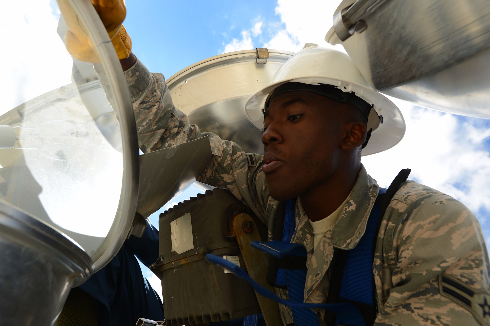 U.S. Air Force Airman 1st Class Ernest Kuma, 20th Civil Engineer Squadron electrical systems apprentice, pulls up the cover on a ramp light along the flightline at Shaw Air Force Base, S.C., Oct. 16, 2014. Each of the 24 ramp lights have covers to protect the bulbs from harsh weather and birds. (U.S. Air Force photo by Airman 1st Class Jensen Stidham/Released)