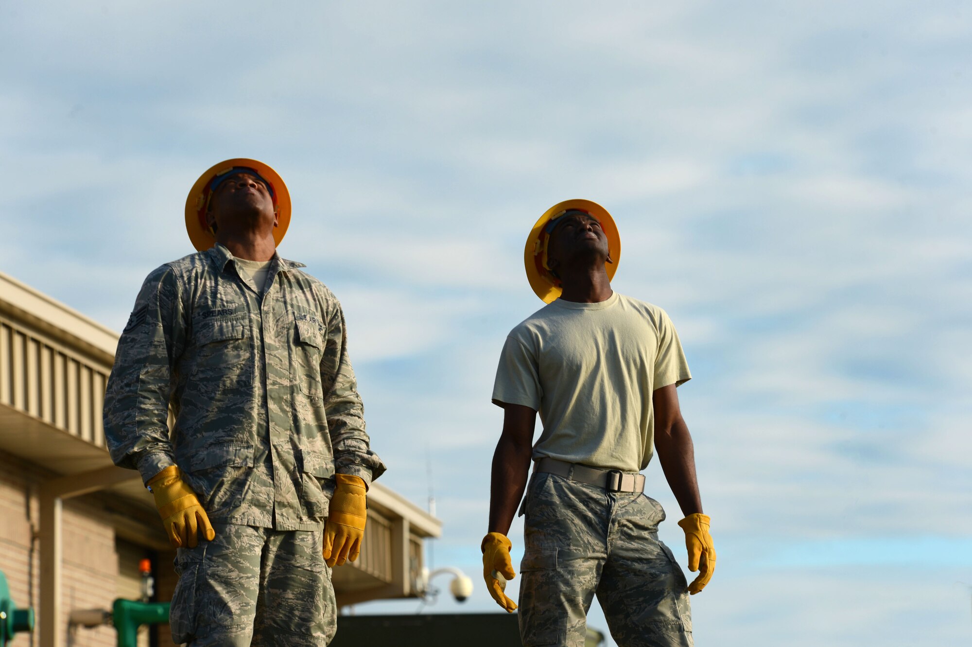 (From left) U.S. Air Force Staff Sgt. Rafael Spears, 20th Civil Engineer Squadron electrical systems craftsman, and Airman 1st Class Ernest Kuma, 20th CES electrical systems apprentice, look up at an Airman climbing a ramp tower at Shaw Air Force Base, S.C., Oct. 16, 2014. To complete maintenance on the ramp tower lights, two Airmen climbed the 110 foot pole. (U.S. Air Force photo by Airman 1st Class Jensen Stidham/Released)