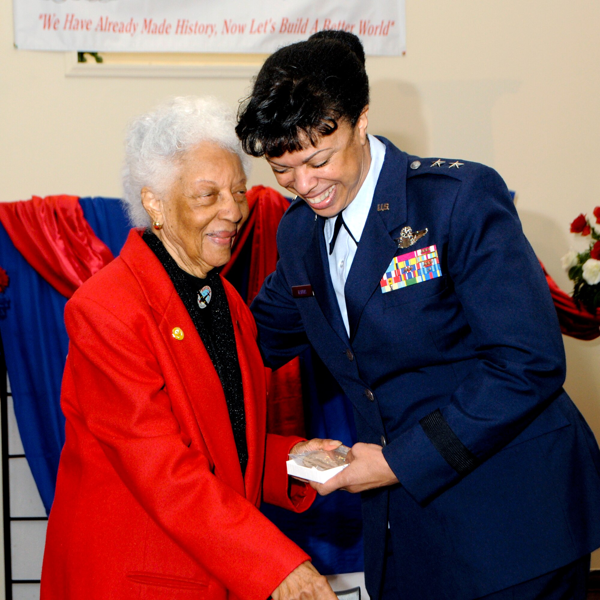 Maj. Gen. Stayce Harris, 22nd Air Force commander, shares a smile with Irma Dryden, an original Tuskegee Airmen, during the presentation of a Congressional Gold Medal replica on Nov. 11, 2014. The medal was presented to Dryden by Harris during the Veterans Day Appreciation Celebration held at the Prince Hall Grand East in Riverdale, Georgia. (U.S. Air Force courtesy photo by Don Alexander/Released)
