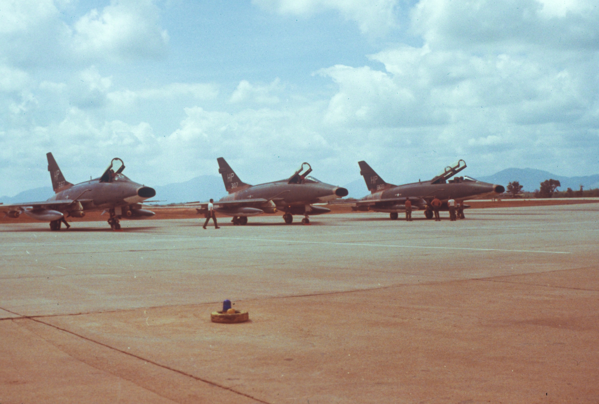 A picture of three U.S. Air Force F-100 Super Sabres from the 355th Tactical Fighter Squadron being looked by maintenance personnel.