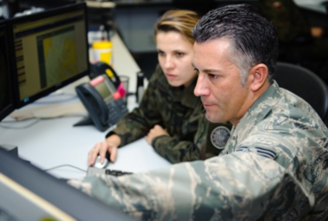 U.S. Air Force Staff Sgt. James Yonko, 21st Operational Weather Squadron regional forecaster supervisor, shows 2nd Lt. Monika Kaczanowska, Polish armed forces meteorological and oceanographic officer, how to read and use weather predictions from the 21st Operational Weather Squadron for Europe and Africa on Kapaun Air Station, Kaiserslautern, Germany, Nov. 14, 2014. U.S. Air Force photo by Senior Airman Armando A. Schwier-Morales