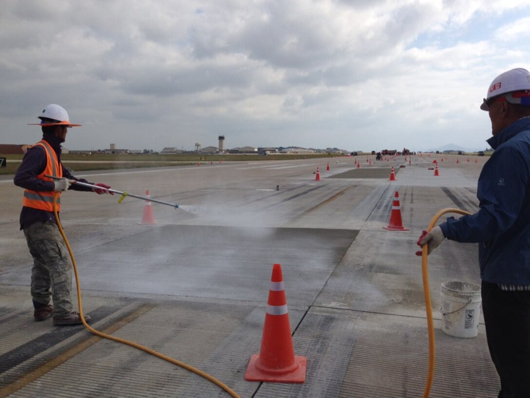 Contractors from Yi Bon Construction Company LTD., apply a compound to prevent the loss of moisture while the concrete is curing on the Kunsan Air Base runway.  If the concrete is exposed to air during the curing process, it will lose moisture and the compressive strength of the concrete will be reduced.