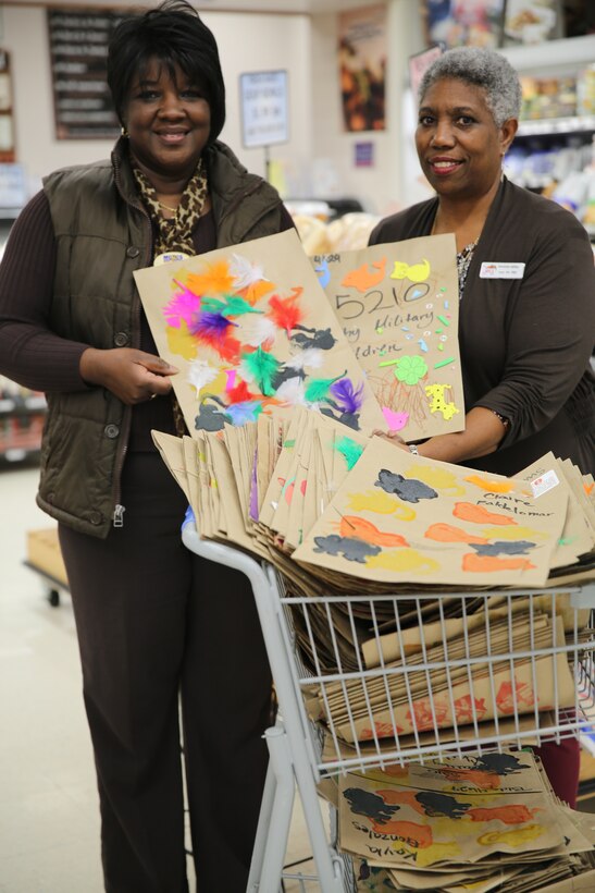 Laverne McKinney, left, and Annette Miller hold bags decorated by children at the Child Development Center at Marine Corps Air Station Cherry Point, N.C., Nov. 14, 2014. The commissary donated the paper bags to the CDC to help raise awareness about the 5210 Healthy Military Children Campaign. McKinney is the director of Cherry Point’s Child Development Center and Miller is a commissary employee.  