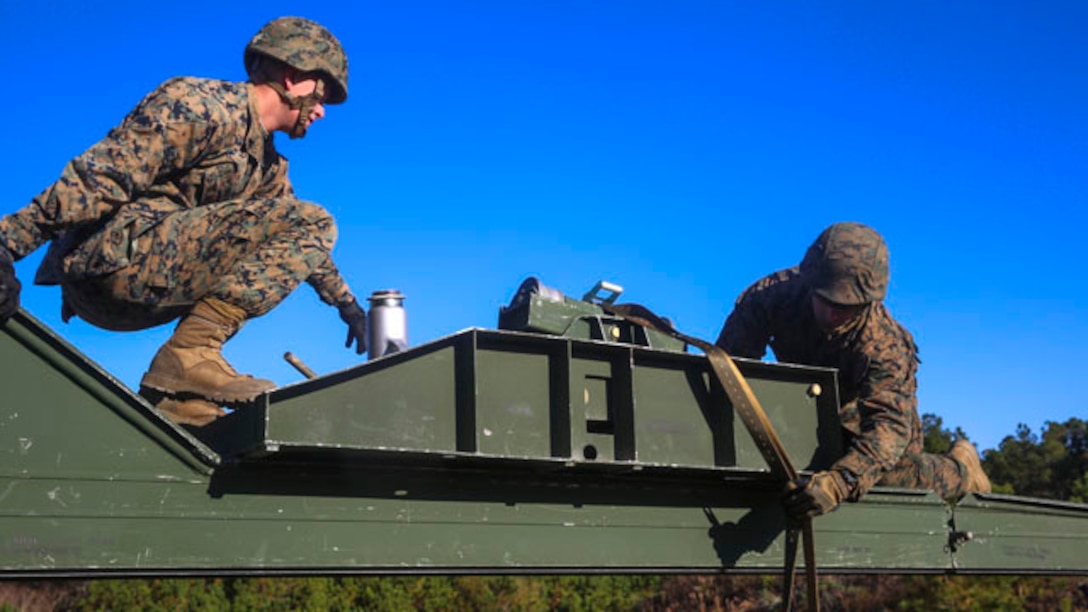 Cpl. Brandon Hunsinger, a combat engineer with 8th Engineer Support Battalion, 2nd Marine Logistics Group, and Philadelphia native, helps Lance Cpl. Adam Thomas, a combat engineer with the unit and a Cambridge, Md. native, to build the nose of the bridge at Landing Zone Dove on Marine Corps Base Camp Lejeune, N.C., Nov. 19, 2014.  Marines with the unit built a 12-bay, double-story, medium-girder bridge in less than six hours.  The training reinforced skills taught in Marine Corps combat engineering school. (Marine Corps photo by Lance Cpl. Kirstin Merrimarahajara/released)