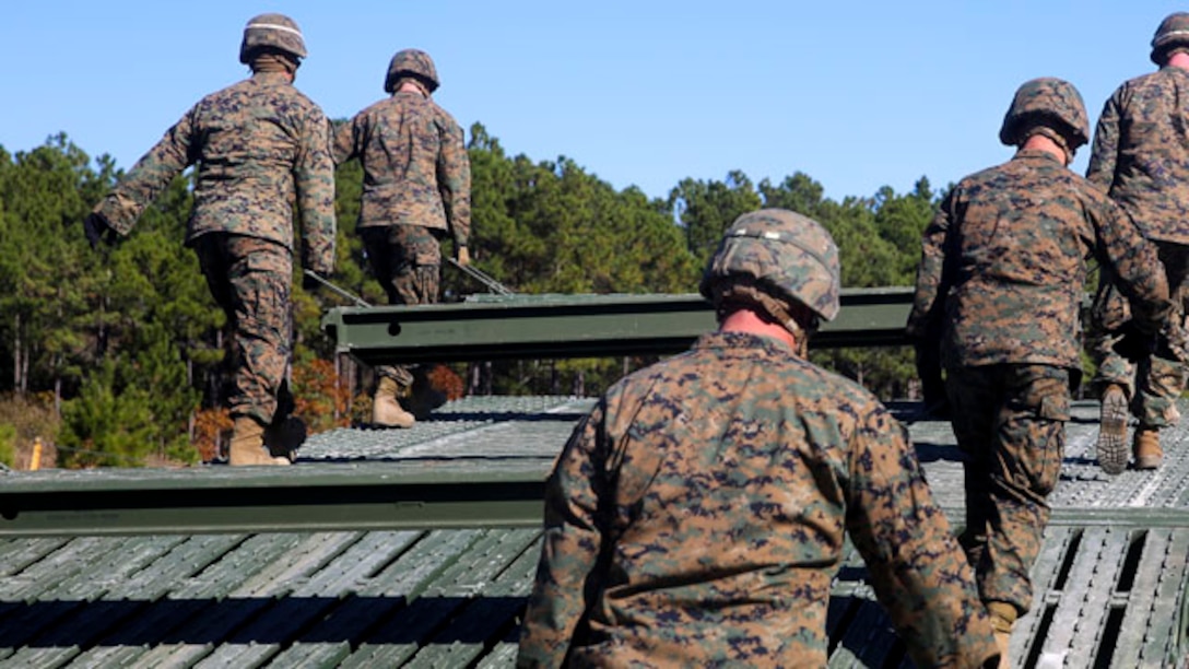 Marines with 8th Engineer Support Battalion, 2nd Marine Logistics Group, install the deck portion of a 12-bay, double-story, medium-girder bridge at Landing Zone Dove on Marine Corps Base Camp Lejeune, N.C., Nov. 19, 2014.  Marines finished the construction in less than six hours.  The training reinforced Marines skills in building a bridge that can support the weight of a tank. (Marine Corps photo by Lance Cpl. Kirstin Merrimarahajara/released)