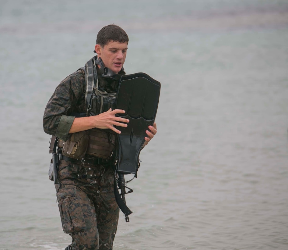 Lance Cpl. Hayden Schuljak, from Crestline, California, carries his gear ashore after swimming 4,000 meters Nov. 18 during a pre-combatant diver course at Camp Schwab. Schuljak was the first Marine to complete the open water exercise. This is one of the many techniques that Marines were taught during the training that prepared them for The Marine Corps Combatant Diver Course. This type of training ensures that when a Marine Expeditionary Unit needs stealthy beach raiding capabilities, the Recon Marines are ready. Schuljak is a reconnaissance man with Company A, 3rd Reconnaissance Battalion, 3rd Marine Division, III Marine Expeditionary Force. 