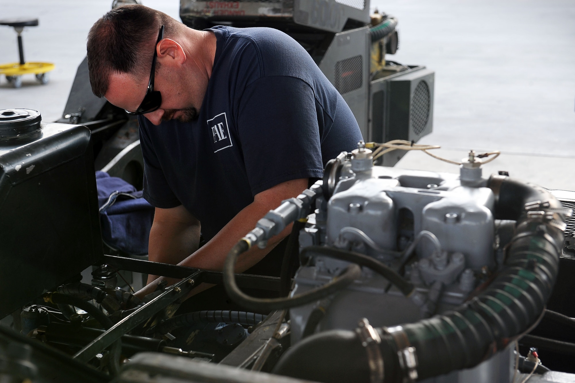 Ed Maloney, a contractor with the 57th Maintenance Group, wraps wires on a bomb lift at the AGE hangar on Nellis Air Force Base, Nev., Nov. 20, 2014. AGE workers stencil and mark AGE as well as service equipment with fuel, oil, coolant, water, hydraulic fluid and air. (U.S. Air Force photo by Airman 1st Class Rachel Loftis)  