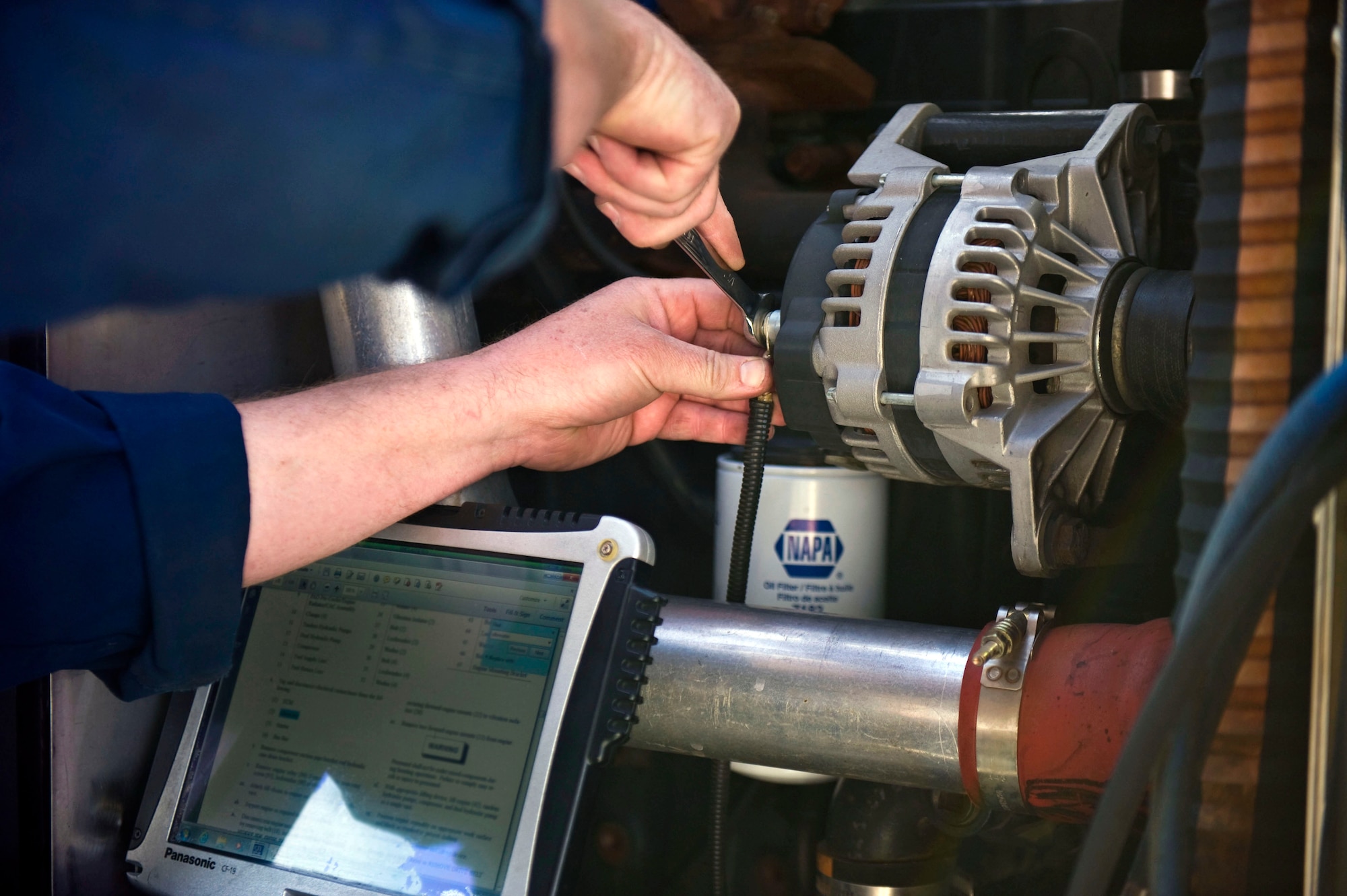 Adam Fisher, a contractor with the 57th Maintenance Group, fixes an alternator wire on a Poly Alpha Olefins cart in the Aerospace Ground Equipment hangar on Nellis Air Force Base, Nev., Nov. 20, 2014. AGE workers support the Air Force mission with their expertise of maintaining, fixing and troubleshooting flightline support equipment. (U.S. Air Force photo by Airman 1st Class Mikaley Towle)  