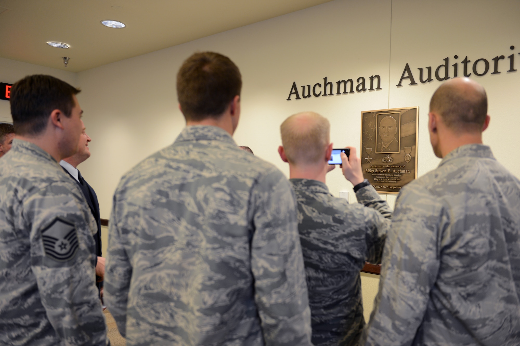Service members from the 5th Air Support Operations Squadron view and take photos of the Auchman plaque Nov. 21, 2014, after the Auchman Auditorium Dedication Ceremony at Joint Base Lewis-McChord, Wash. Master Sgt. Steven Auchman was a maintenance superintendent at the 5th ASOS who lost his life during a Nov. 9, 2004 mortar attack in Mosul, Iraq. (U.S. Air Force photo/Airman 1st Class Keoni Chavarria)