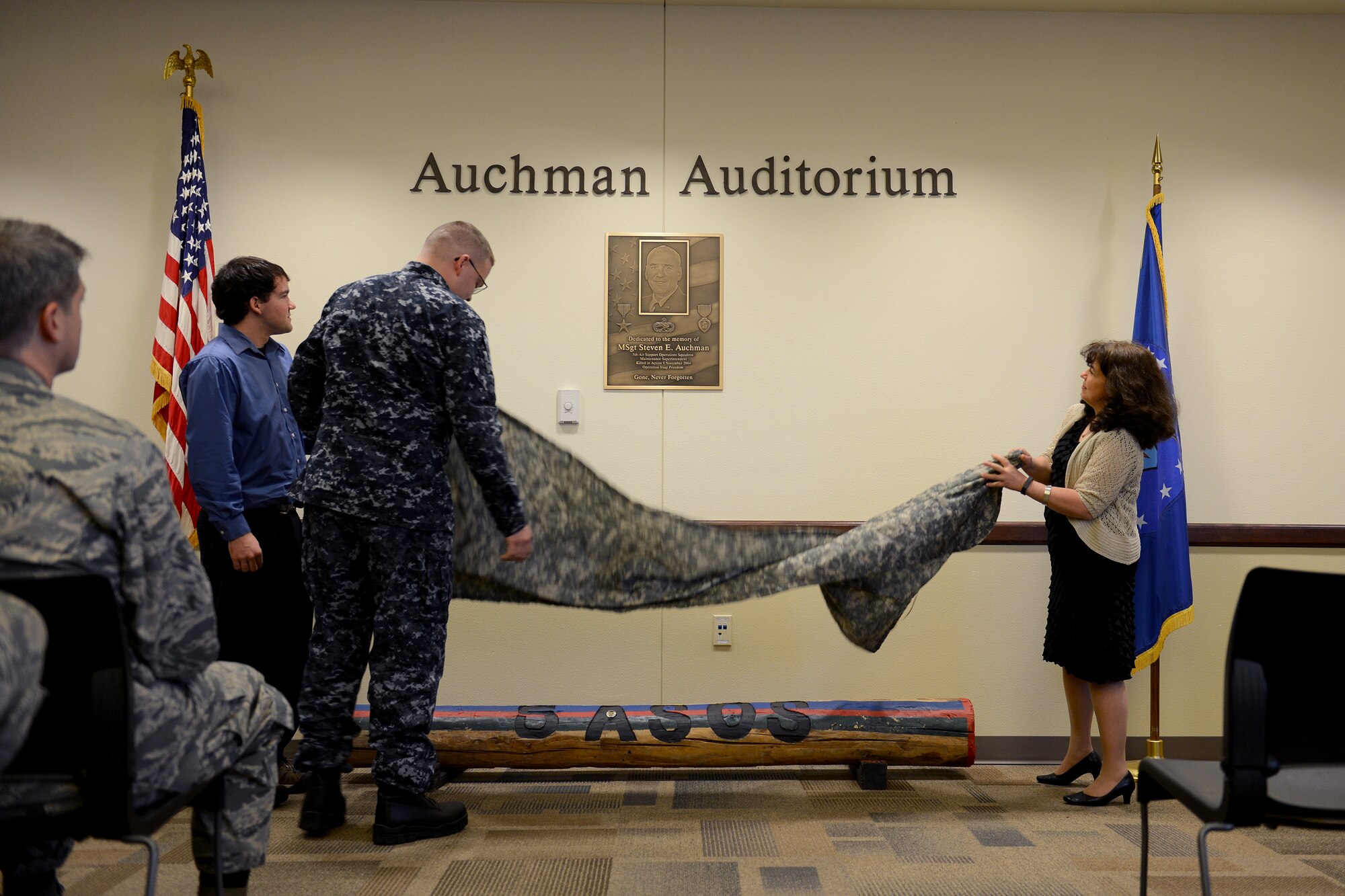 From left to right, Eric, Brian, and Jennifer Auchman, family members of Master Sgt. Steven Auchman, uncover a plaque, Nov. 21, 2014, during the Auchman Auditorium Dedication Ceremony at Joint Base Lewis-McChord Wash. After uncovering the plaque, Jennifer shared a few words with the 5th ASOS before concluding the ceremony. (U.S. Air Force photo/Airman 1st Class Keoni Chavarria)
