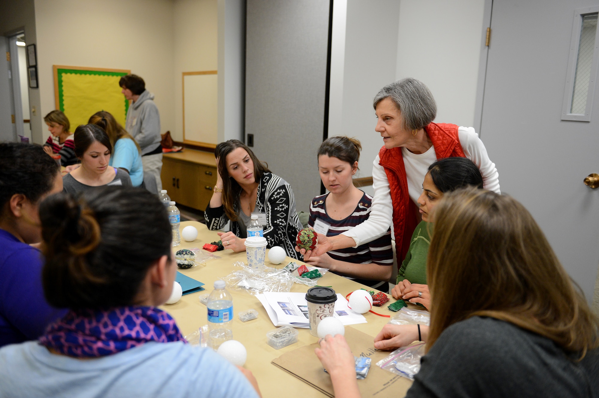 Margie Nabours, Protestant Women of the Chapel craft teacher, displays a finished product to attendants, Nov. 22, 2014, during the Craft Tea event at the Chapel Support Center at Joint Base Lewis-McChord, Wash. The event had seven different classes that ranged from the “Better than “Hallmark Class” where they created homemade cards to the creating “Gifts in a Jar Class” where they filled jars with food mixes. (U.S. Air Force photo/Airman 1st Class Keoni Chavarria)