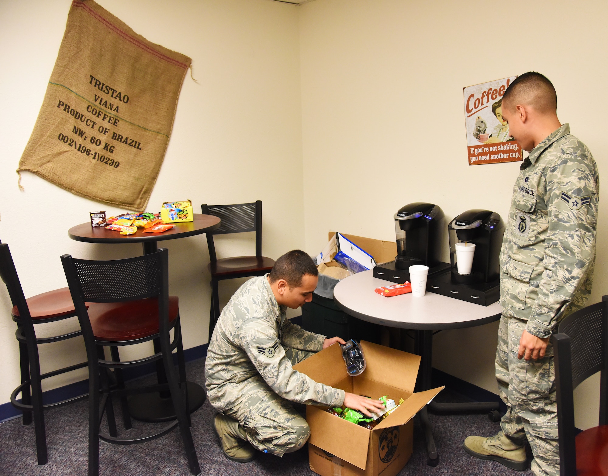 Two of Malmstrom’s security forces personnel look through a donated care package while grabbing a cup of coffee in the new Holy Joe’s Café Nov. 20. Since its implementation, Holy Joe’s Café is already serving more than 500 cups of coffee per week to Airmen. (U.S. Air Force photo/ Airman 1st Class Collin Schmidt)