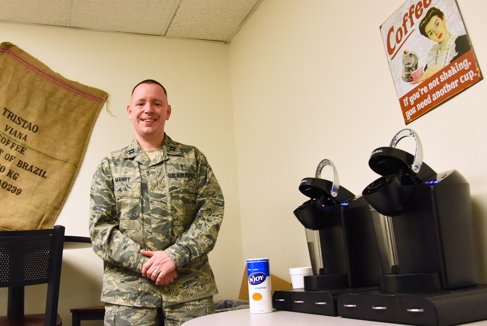 Chaplain (Capt.) Keith Manry, 341st Missile Wing chaplain for the security forces group, stands next to two, brand-new coffee machines in the recently opened Holy Joe’s Café in Bldg. 500 on Nov. 19. Holy Joe’s was implemented to provide an oasis for defenders to visit before and after posting to the missile field, the weapons storage area or base side. (U.S. Air Force photo/ Airman 1st Class Collin Schmidt)