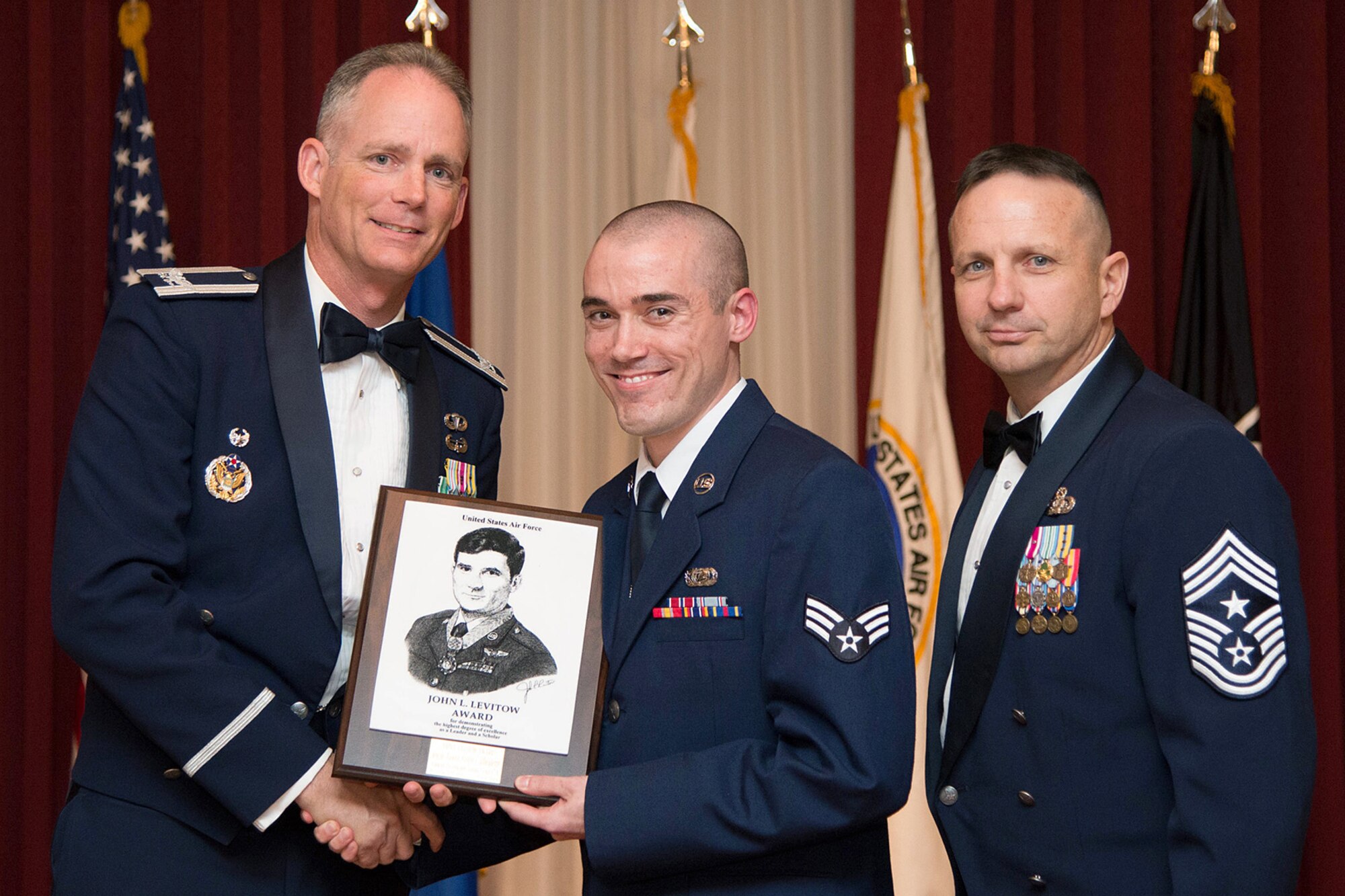 Senior Airman Steven J. Morissette is presented the John L. Levitow Award from Col. Michael A. Vogel (left), 66th Air Base Group commander, and Hanscom Command Chief Master Sgt. Craig A. Poling (right) during the Airman Leadership School graduation ceremony at the Minuteman Commons Nov. 21. Morissette and 11 others completed the five week Professional Military Education class designed to develop junior enlisted members into effective front-line supervisors. (U.S. Air Force photo by Linda LaBonte Britt)