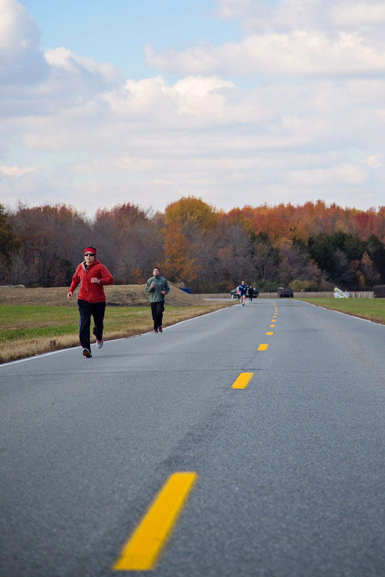 709th Airlift Squadron loadmaster, Tech. Sgt. Carolina Rodriquez, leads a group running down the parimeter road on Dover AFB, Dover, during a  fitness run Nov. 14. Rodriquez organized a group of 25 people to participate in the "Across the Bay 10K" race this Nov. to help raise money for the charity War Dogs Making it Home, an organization that pairs war dogs with veterans with PTSD and TBI. 