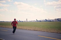 709th Airlift Squadron loadmaster, Tech. Sgt. Carolina Rodriquez, runs down the parimeter road on Dover AFB, Dover, during a group fitness run Nov. 14. Rodriquez organized a group of 25 people to participate in the "Across the Bay 10K" race this Nov. to help raise money for the charity War Dogs Making it Home, an organization that pairs war dogs with veterans with PTSD and TBI. (U.S. Air Force photo by Capt. Bernie Kale)