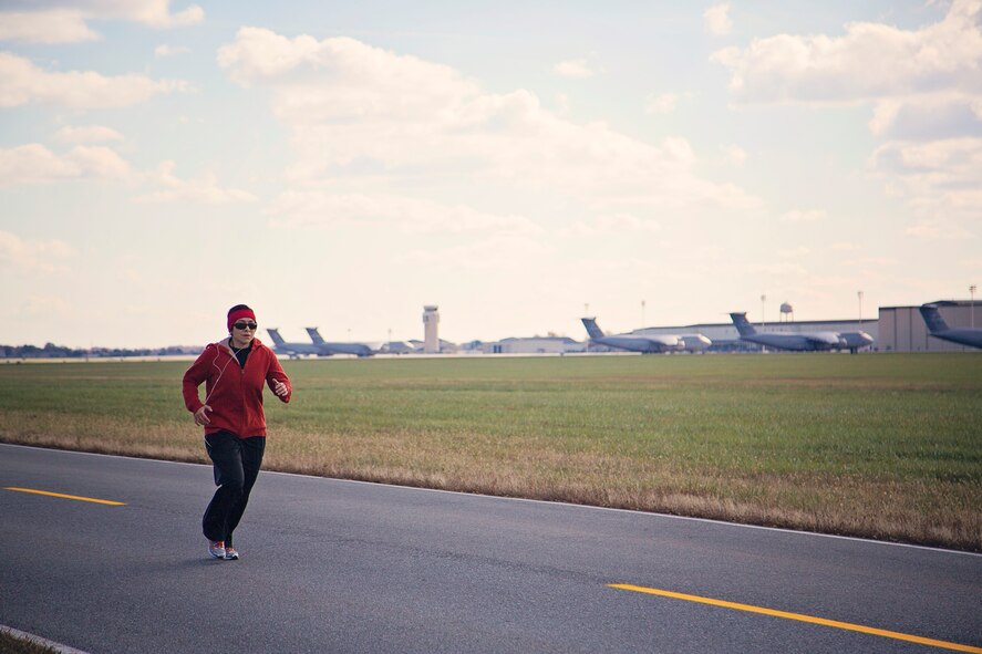 709th Airlift Squadron loadmaster, Tech. Sgt. Carolina Rodriquez, runs down the parimeter road on Dover AFB, Dover, during a group fitness run Nov. 14. Rodriquez organized a group of 25 people to participate in the "Across the Bay 10K" race this Nov. to help raise money for the charity War Dogs Making it Home, an organization that pairs war dogs with veterans with PTSD and TBI. (U.S. Air Force photo by Capt. Bernie Kale)
