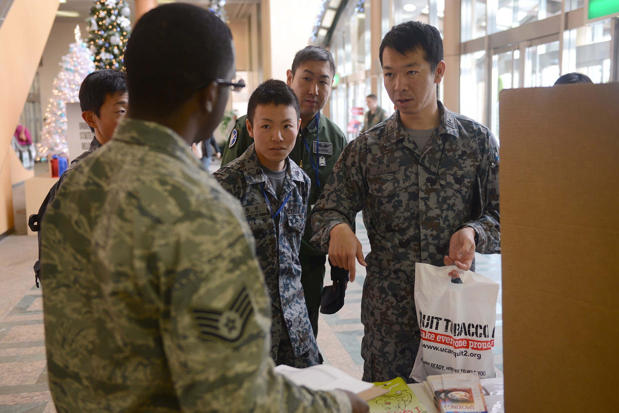 Japan Air Self-Defense Force members ask Staff Sgt. Anthony Washington, 374th Aerospace Medicine Squadron health promotion flight NCO in charge, about the Great American Smokeout Campaign at Yokota Air Base, Japan, Nov. 20, 2014. The campaign focuses on encouraging people to quit smoking and is part of the Healthy Base Initiative. (U.S. Air Force photo by Airman 1st Class David C. Danford/Released)