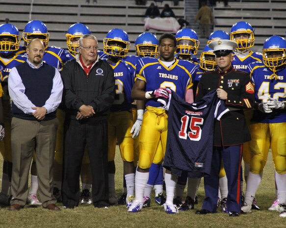 Nyheim Hines, a running with the Garner High School football team is presented a jersey during his Semper Fidelis All-American Bowl Jersey presentation at Garner High School in Garner, North Carolina by U.S. Marine Corps Sgt. Matthew Smith, a recruiter with Recruiting Station Raleigh. Hines was selected to play in the bowl for his skill as a running back, his academics and his leadership ability.  The Semper Fidelis All-American Bowl allows the Marine Corps to engage with well-rounded student athletes and share leadership lessons that will enable future success. It will be played on Jan. 4, 2015, in Carson, California, and will be broadcast on Fox Sports 1. (U.S. Marine Corps photo by Sgt. Dwight A. Henderson/Released) 