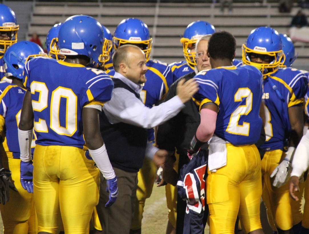 Nyheim Hines, a running with the Garner High School football team is presented a jersey during his Semper Fidelis All-American Bowl Jersey presentation at Garner High School in Garner, North Carolina by U.S. Marine Corps Sgt. Matthew Smith, a recruiter with Recruiting Station Raleigh. Hines was selected to play in the bowl for his skill as a running back, his academics and his leadership ability.  The Semper Fidelis All-American Bowl allows the Marines of Marine Corps Recruiting Station Raleigh to engage with well-rounded student athletes and share leadership lessons that will enable future success. It will be played on Jan. 4, 2015, in Carson, California, and will be broadcast on Fox Sports 1. (U.S. Marine Corps photo by Sgt. Dwight A. Henderson/Released) 