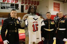 Brandon Tiassum, a defensive tackle with Park Tudor High School, presents his jersey at the school’s fall awards assembly, Nov. 21, 2014, after being officially recognized to participate in the 2015 Semper Fidelis All-American Bowl. Capt. Joseph A. Haley (left) presented the jersey to Tiassum, alongside Staff Sgt. Gene E. Bradley (center), Master Gunnery Sgt.  Andrew Korous (right). (Photo by Sgt Tyler Mitchell)


