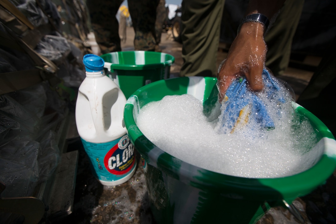 A U.S. Marine with SPMAGTF - Crisis Response - Africa soaks a rag into a bucket of water that contains bleach and soap, in accordance with Centers for Disease Control and Prevention cleaning and decontamination guidelines, before washing equipment as part of the standard procedure prior to leaving the country, while in support of Operation United Assistance in Monrovia, Liberia, Nov. 19, 2014. United Assistance is a Department of Defense operation to provide command and control, logistics, training and engineering support to U.S. Agency for International Development- led efforts to contain the Ebola virus outbreak in West African nations. (U.S. Marine Corps photo by Lance Cpl. Andre Dakis/SP-MAGTF Crisis Response Africa Combat Camera/Released)