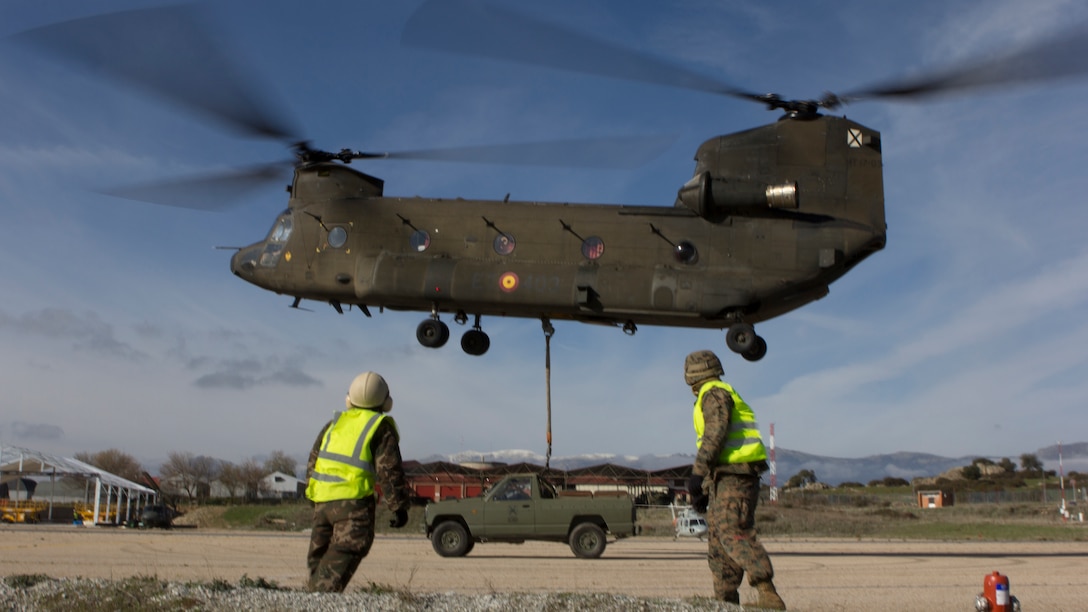 A U.S. Marine with SPMAGTF Crisis Response - Africa and a Spanish soldier with Transport Helicopter Battalion 5, watch a Spanish Army CH-47 Chinook lift a truck that they had attached its bottom at Colmenar de Viejo, Spain, Nov. 18, 2014. The long distance transportation of vehicles by air can be used when conducting a disaster relief mission where vehicles are needed but key road and bridges are destroyed. The training conducted by the Marines and soldiers enhanced mission readiness and help build relationships between the two militaries. (U.S. Marine Corps photo by Cpl Jeraco Jenkins/Released).