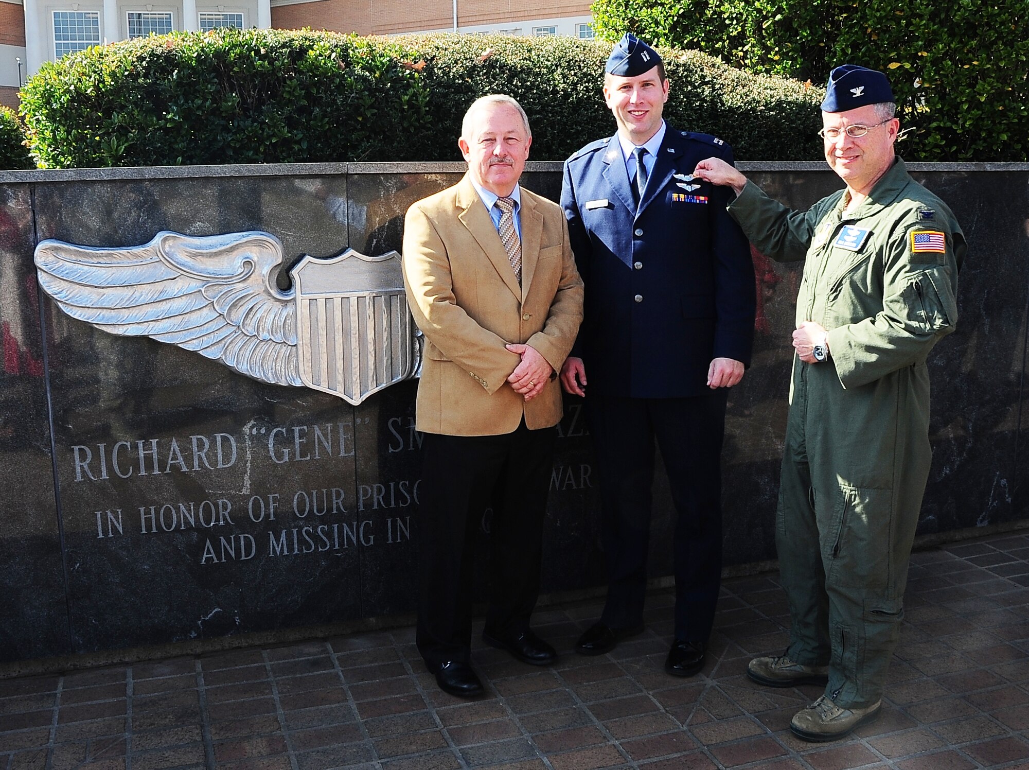 Col. Bill Mueller pins the silver wings of an Air Force pilot to the chest of Capt. William Smith with the assistance of Smith’s father, Mike, at the Gene Smith Memorial Plaza Nov. 21, 2014, on Columbus Air Force Base, Miss. Mueller visited the base to congratulate and welcome Smith into the pilot-physician program, an elite career field combining two very specialized jobs. Mueller is the director of the Air Force pilot-physician program at Wright-Patterson Air Force Base, Ohio. Smith is a 14th Flying Training Wing Specialized Undergraduate Pilot Training Class 15-02 student and a prior flight surgeon. (U.S. Air Force photo/Airman Basic John Day)