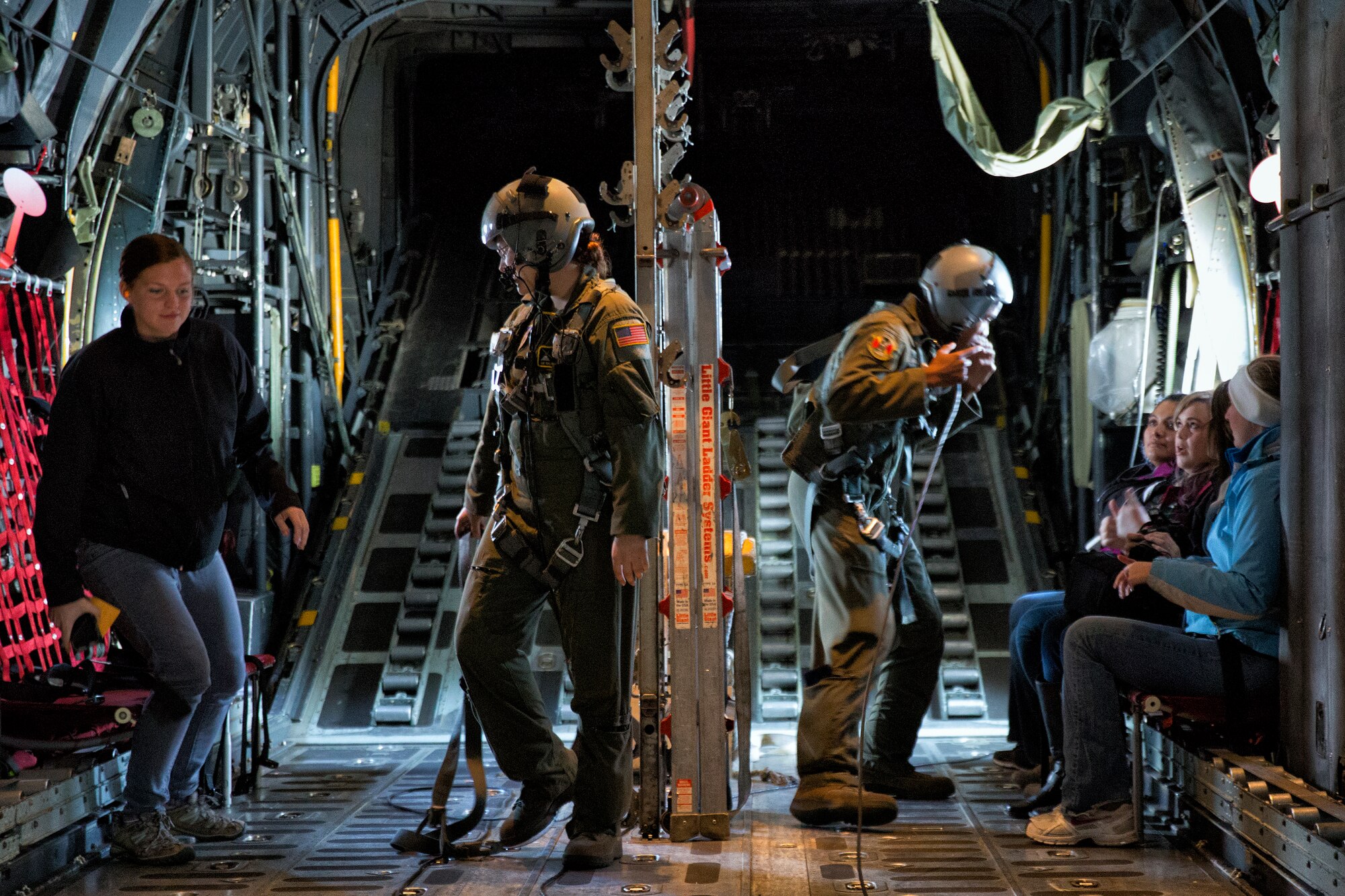(Left to right) Senior Airman Taylor Hubstenberger and SrA Adrian Robinson, both 36th Airlift Squadron loadmasters, guide spouses during Operation VOLANT SPOUSE 14’ over the Kanto Plain, Nov. 24, 2014. The spouses had the opportunity to fly on the C-130 Hercules, UH-1N Huey and C-12 Huron as part of a spouse orientation day. (U.S. Air Force photo by Osakabe Yasuo/Released)