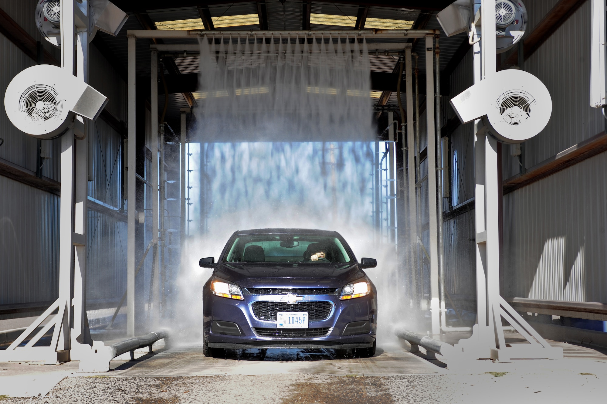 U.S. Air Force Senior Airman Andrew Liszewski, 355th Logistics Readiness Squadron vehicle operator and dispatcher, drives a government-owned vehicle through the wash rack at Davis-Monthan Air Force Base, Ariz., Nov. 18, 2014. The high-pressure water from the wash clears the car of dust and dirt before detailing begins. (U.S. Air Force photo by Airman 1st Class Cheyenne Morigeau/ Released)