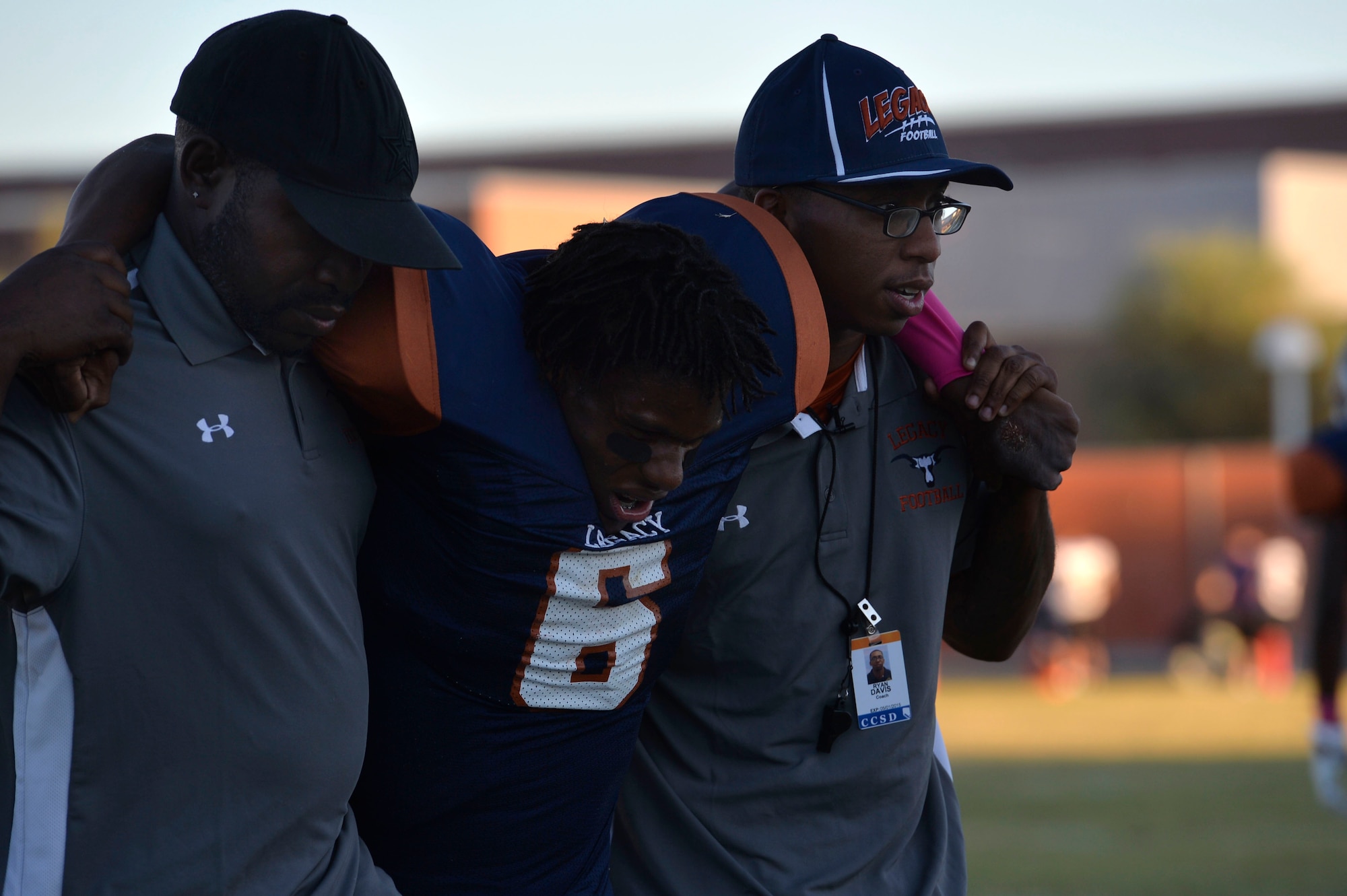 Staff Sgt. Ryan Davis, right, and Coach Kevin Evans, Legacy High School football coaches, carry an injured player from the field during a homecoming football game in Las Vegas Oct. 3, 2014. Davis, a 99th Ground Combat Training Squadron combat arms training and maintenance instructor, places utmost importance on the safety of his players since he suffered a motorcycle accident ended his own football career. (U.S. Air Force photo by Tech. Sgt. Nadine Barclay/RELEASED)