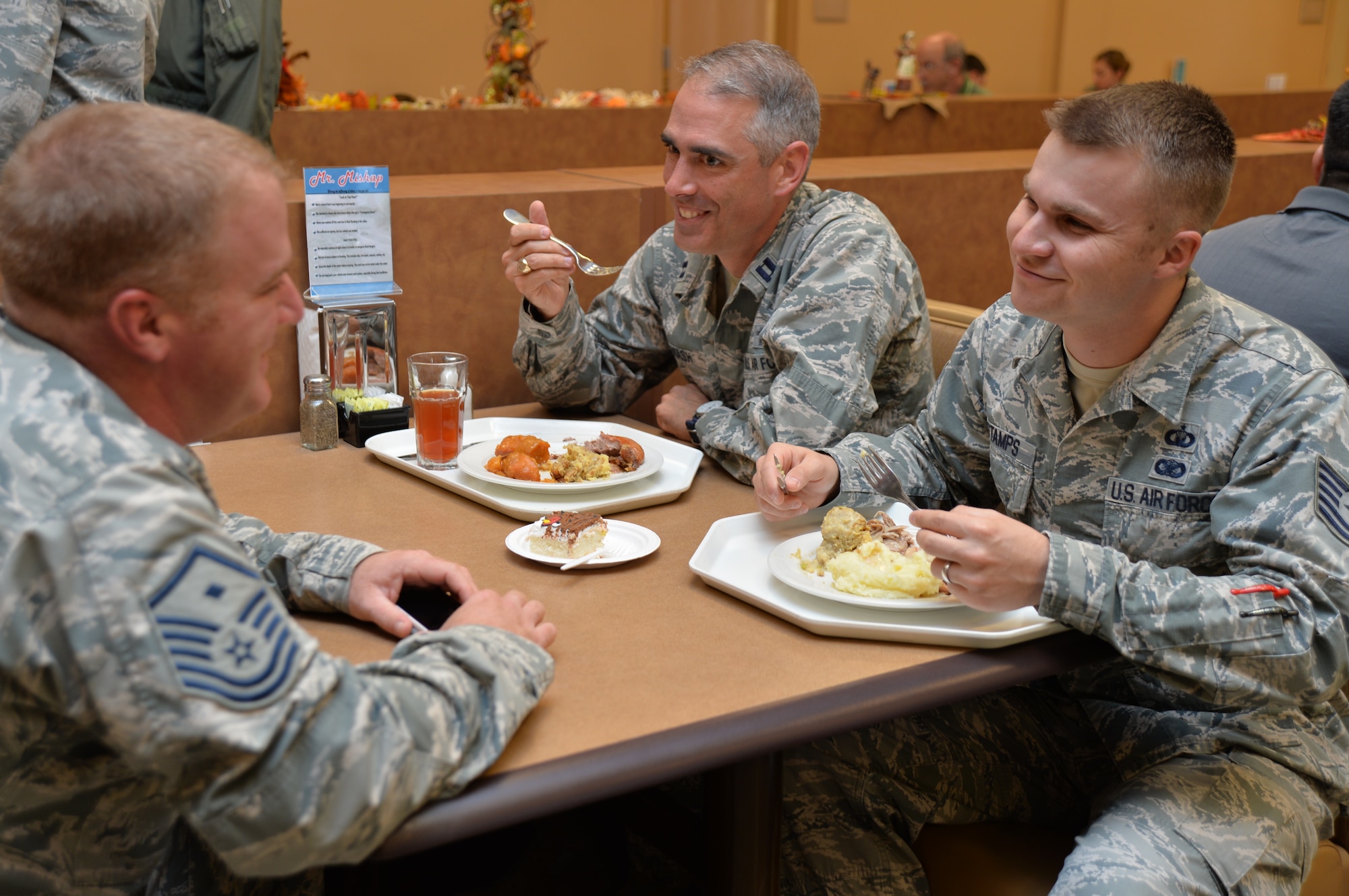 Master Sgt. Bryan, 15th Reconnaissance Squadron first sergeant, left, Chaplain (Capt.) Zachary Nash and Tech. Sgt. Noah Stamps, command chief assistant, talk while enjoying a meal served during a Thanksgiving celebration at Creech Air Force Base, Nevada, Nov. 18, 2014. The wing hosted the event as a way to thank Airmen for their hard work, sacrifices, and dedication to the mission throughout the year. (Some last names have been withheld for security purposes.) (U.S. Air Force photo by Tech. Sgt. Nadine Barclay/released) 

