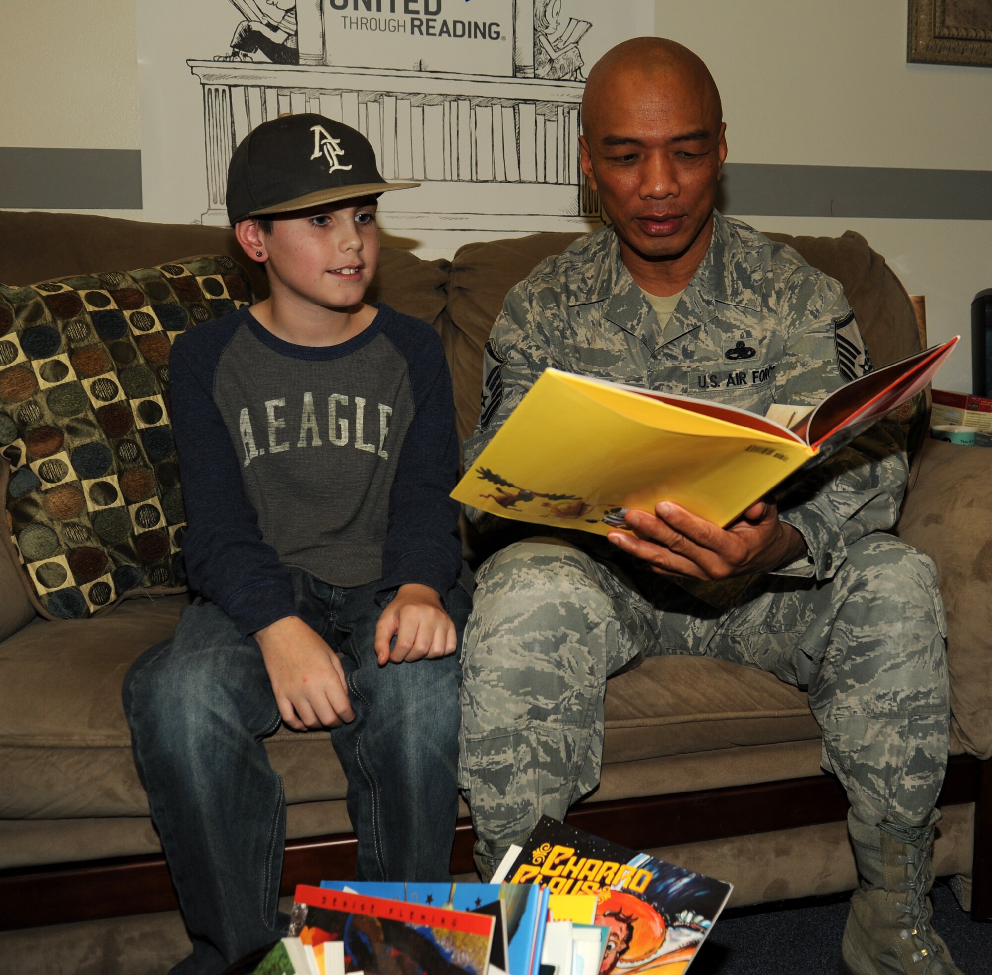 Master Sgt. Rey Ordonio, 92nd Maintenance Squadron assistant flight chief, reads a book to Blake Juarez at the Airman and Family Readiness Center on November 25, 2014 at Fairchild Air Force Base, Wash. The Airman Family Readiness center offers United Through Reading which allows members who are deploying to have a recording made of them reading books. This resource is one of many offered at the A&FRC for families during deployments.  (U.S. Air Force photo/Staff Sgt. Samantha Krolikowski)