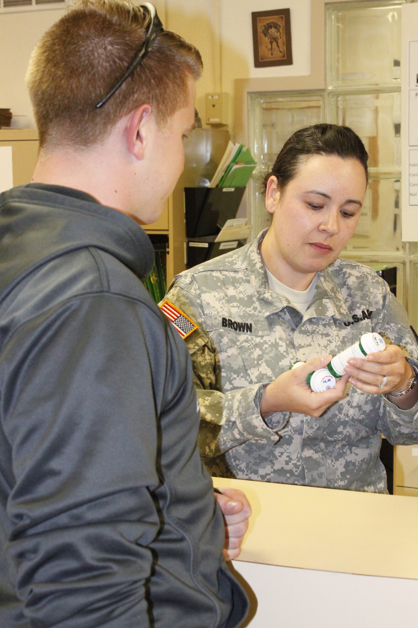 U.S. Army Capt. Tracy Brown, a veterinarian at the Kirtland Animal Treatment Facility, explains to Airman 1st Class Alex Greenawalt how to administer his dog’s medications during a visit to the on-base clinic  (Photo by Meredith Mingledorff) 
