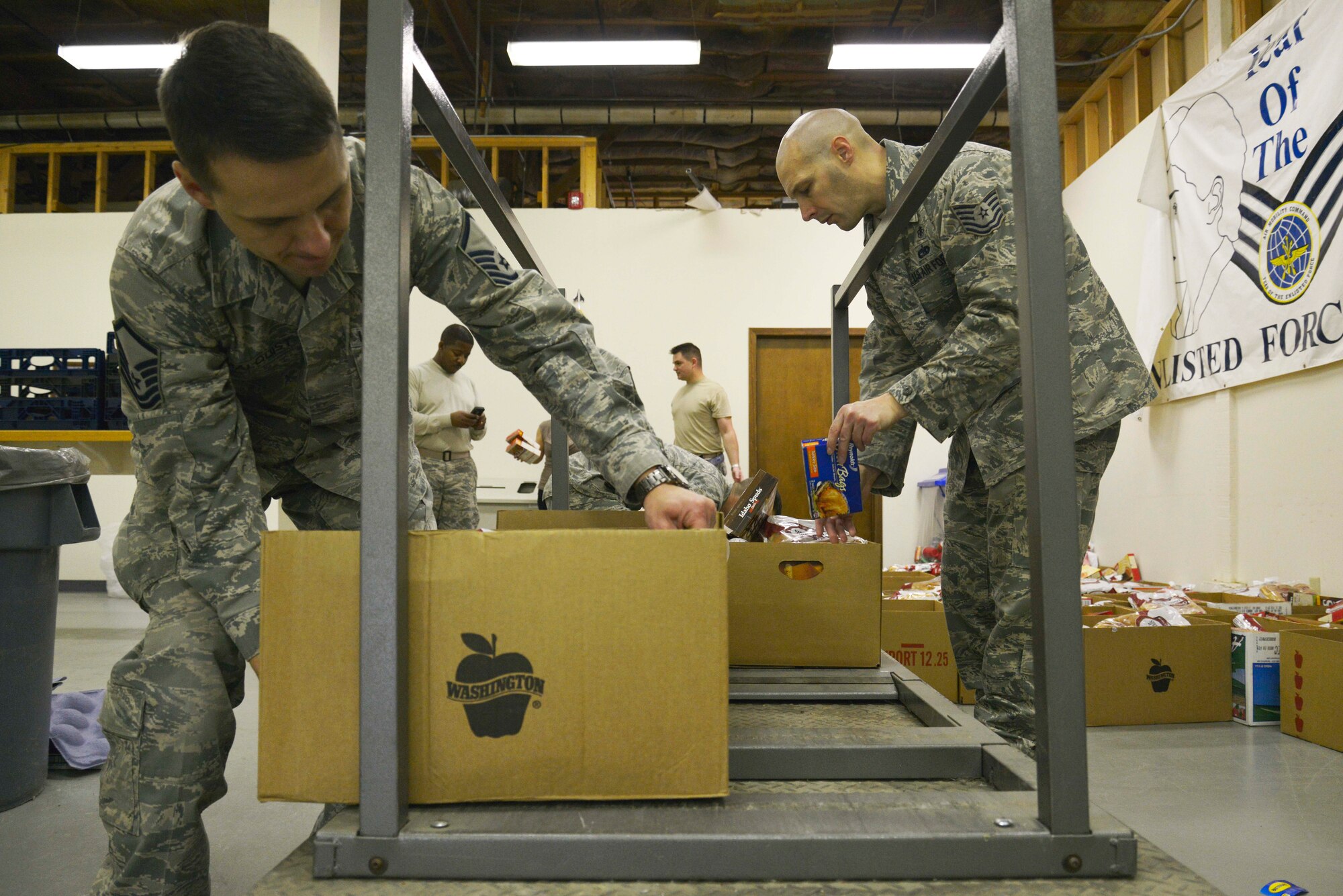 Master Sgt. Raymond Malquist and Tech. Sgt. Dale Kirner, both volunteers, load boxes of complete Thanksgiving meals into a cart to be given to Airmen around base during the First Sergeant’s annual Turkey Drive Nov. 24, 2014, at Fairchild Air Force Base, Wash. Most of the items came from the base commissary and their vendors. Armed Forces Bank, Costco and Global Credit Union also donated goods to support Fairchild Airmen. (U.S. Air Force photo/Airman 1st Class Janelle Patiño)