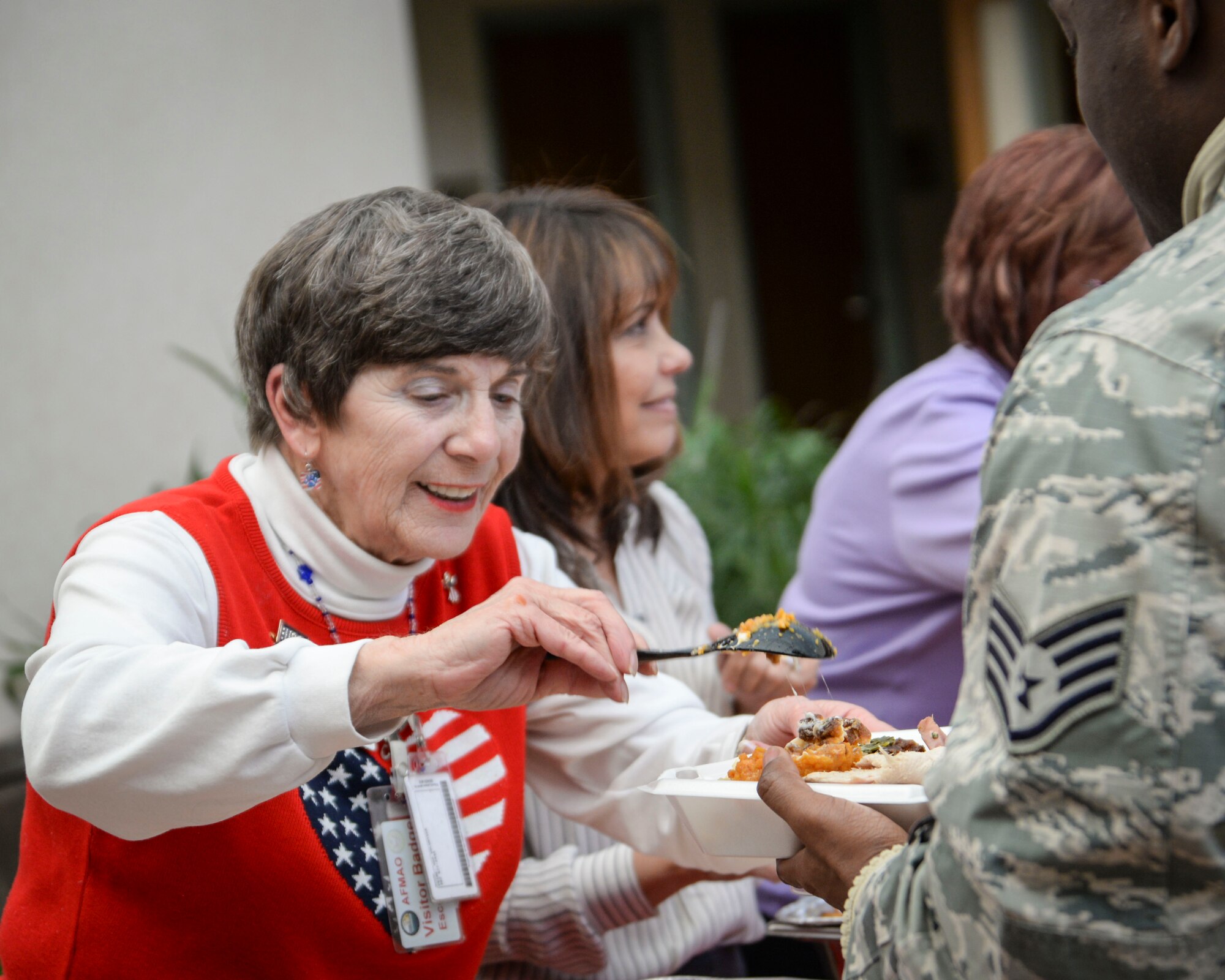 Rosanne Hirth, a USO volunteer, serves food to the team at Air Force Mortuary Affairs Operations during a Thanksgiving meal, Nov. 18, 2014. The USO and its volunteers continuously serve the mortuary staff and families of the fallen who travel to Dover AFB, Del., for the dignified transfer of a loved one.  (U.S. Air Force photo/Capt. Ray Geoffroy)
