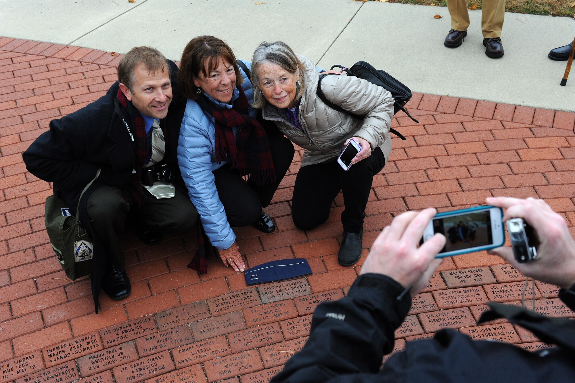 Sean Jarman (left), the son of Capt. William Jarman Jr., an F-4 Phantom pilot with the 335th Tactical Fighter Squadron during the 1960s, who died in 1969 during an aircraft collision over Fort Bragg, North Carolina, takes a photo with family members near a brick with William’s name and service details by the Heritage Park F-15E Strike Eagle memorial fountain at Seymour Johnson Air Force Base, North Carolina, Nov. 14, 2014. Bricks surround the fountain, commemorating heroes from the base’s past. (U.S. Air Force photo/Airman 1st Class Aaron Jenne)