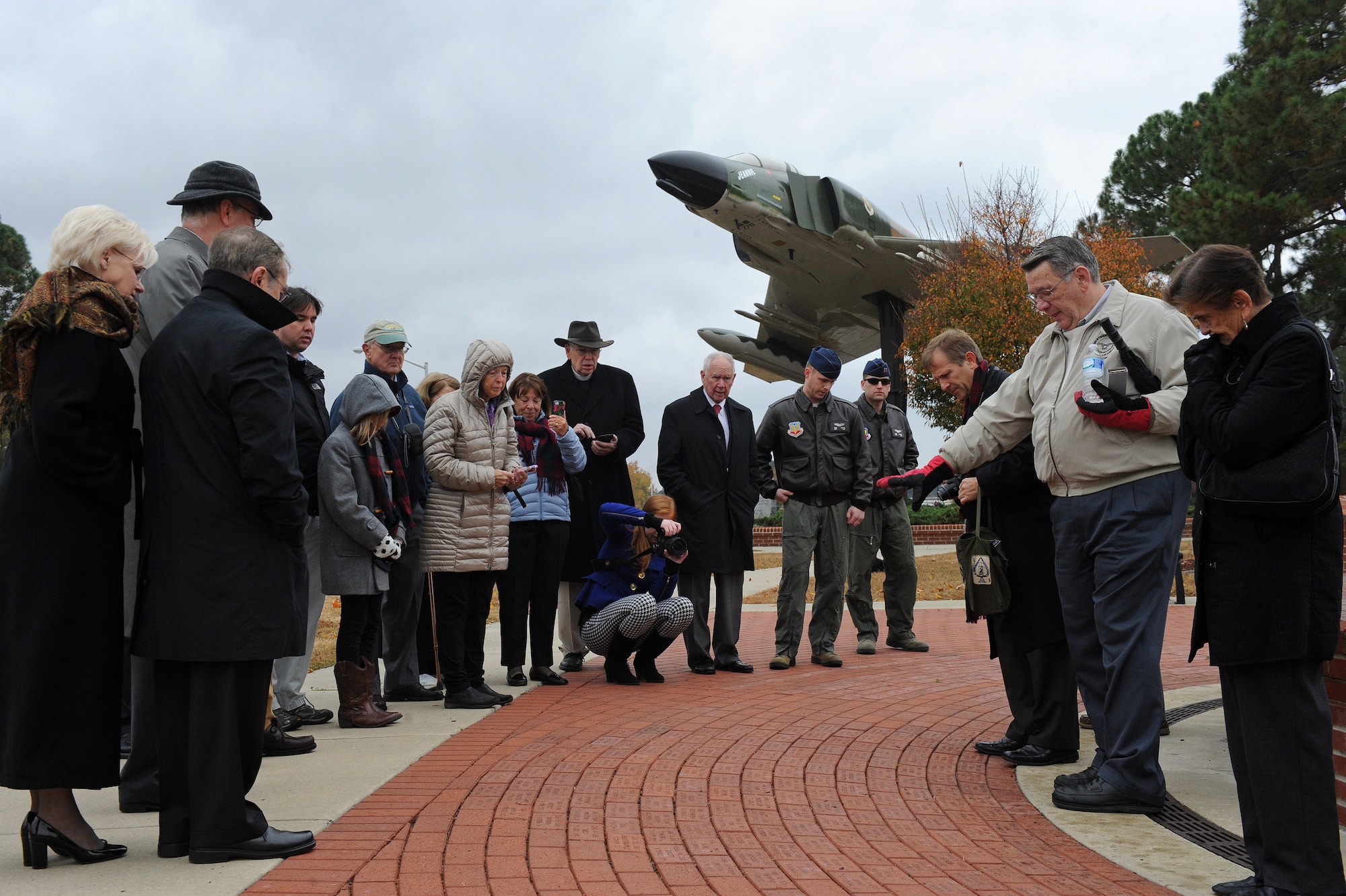 Family and friends of Capt. William Jarman Jr., an F-4 Phantom pilot with the 335th Tactical Fighter Squadron during the 1960s, who died in 1969 during an aircraft collision over Fort Bragg, North Carolina, gather in Heritage Park at Seymour Johnson Air Force Base, North Carolina, during a ceremony where two bricks were dedicated to Jarman’s legacy, Nov. 14, 2014. The bricks are inscribed with his name and service details. Bricks surround the Heritage Park F-15E Strike Eagle memorial fountain, commemorating heroes from the base’s past. Jarman’s family and friends visited the base, Nov. 14, to connect with the Airmen of the 335th Fighter Squadron, a squadron Jarman dedicated his life to. (U.S. Air Force photo/Airman 1st Class Aaron Jenne)