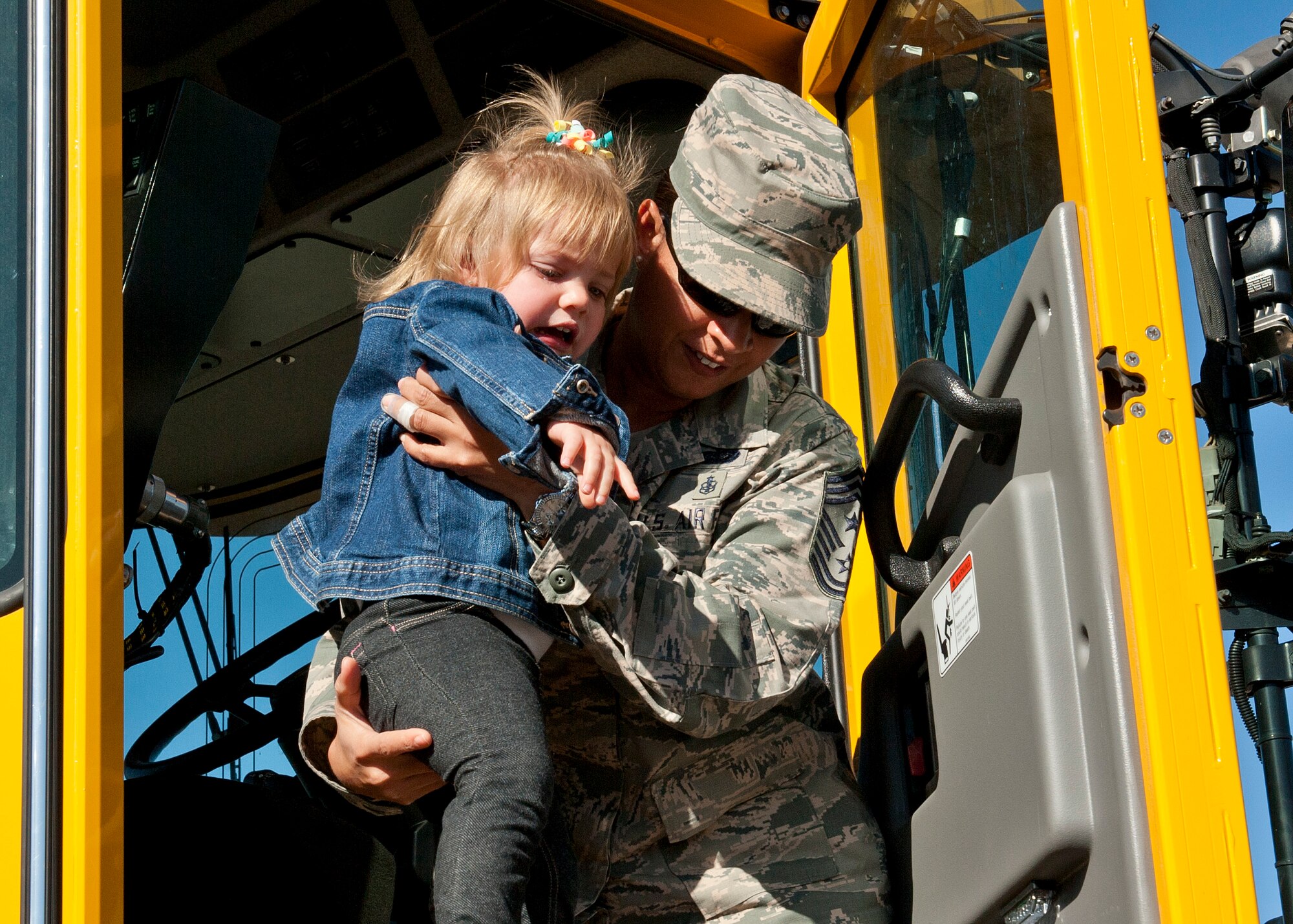 PETERSON AIR FORCE BASE, Colo. – Chief Master Sgt. Idalia Peele, 21st Space Wing command chief, helps a child down after showing her the inside of a snow plow during the 21st Civil Engineer Squadron Snow Parade Oct. 28. Peele attended this and many other events around base since her arrival in June. (U.S. Air Force photo/Airman 1st Class Rose Gudex)