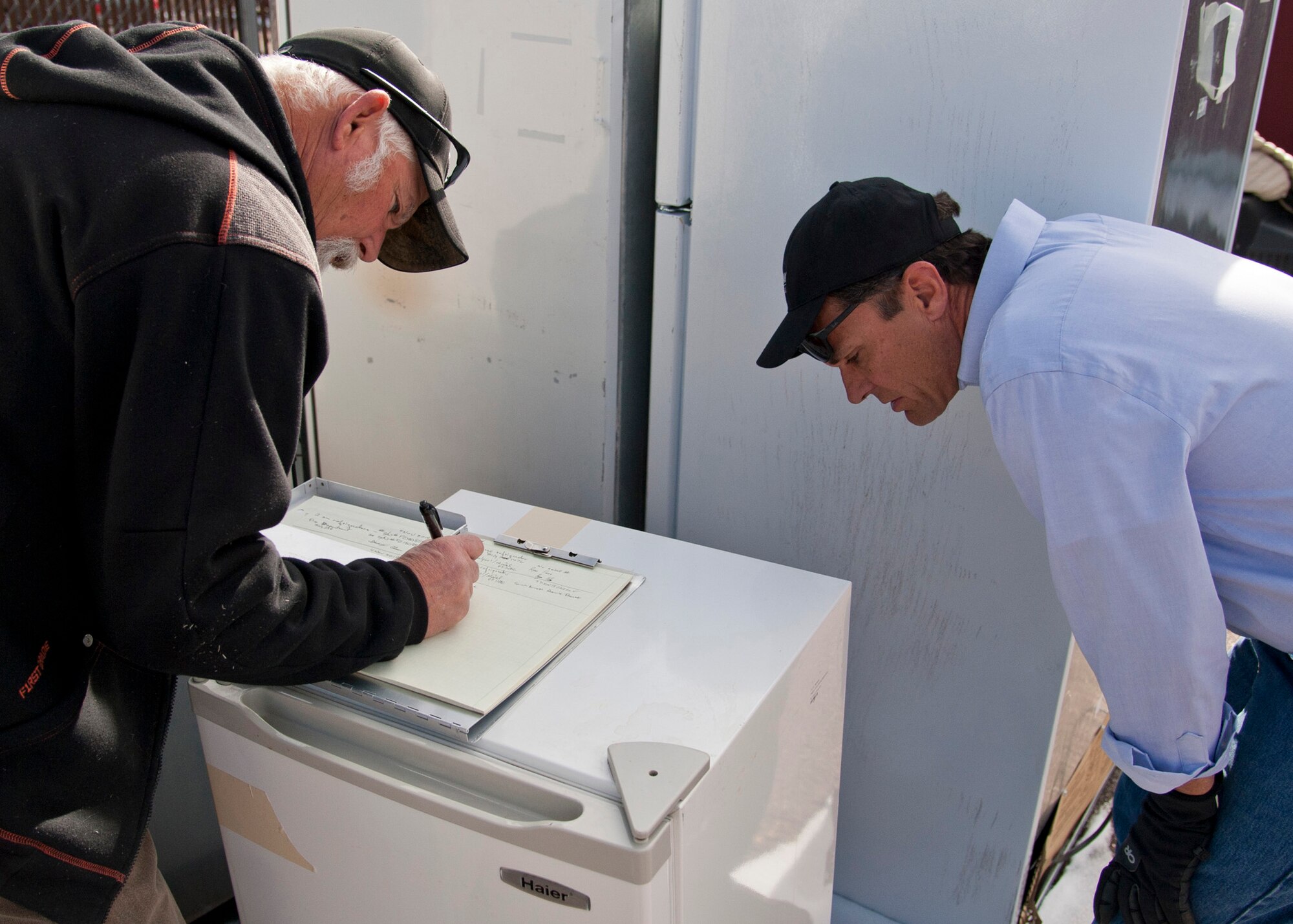 PETERSON AIR FORCE BASE, Colo. – Phil Chase and David Anderson, 21st Civil Engineer Squadron environmental program managers, collect information on the non-compliant refrigerators turned in during the Operation Chill Out, Nov. 18, 2014. The Chill Out was an event where non-compliant refrigerators at 21st Space Wing installations were turned in for recycling or taken to the Defense Logistics Agency at Fort Carson. (Air Force photo by Senior Airman Tiffany DeNault)