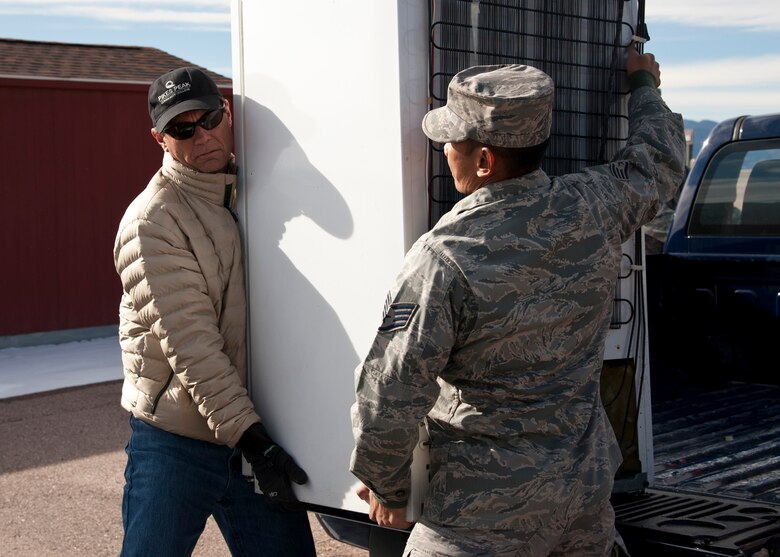 PETERSON AIR FORCE BASE, Colo.- David Anderson, 21st Civil Engineer Squadron, and Staff Sgt. Joseph Swe, 21st Communications Squadron, lift a refrigerator out of a truck bed to put on a pallet at the 21st CES environmental office during Operation Chill Out, Nov. 18, 2014. The Chill Out was an event where non-compliant refrigerators at 21st Space Wing installations were turned in for recycling or taken to the Defense Logistics Agency at Fort Carson. (Air Force photo by Senior Airman Tiffany DeNault)