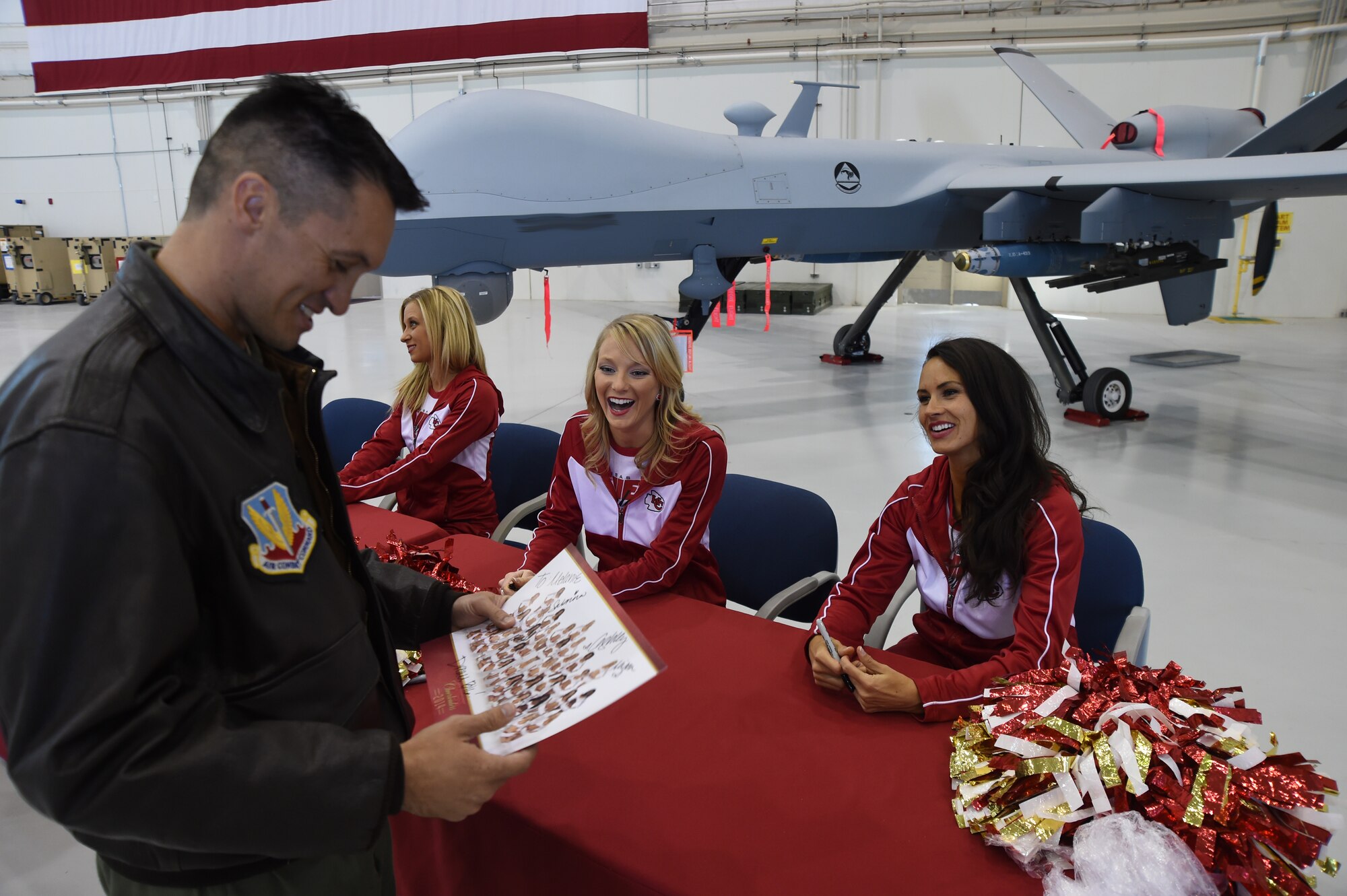 Capt. Eric, 42nd Attack Squadron assistant director of staff, meets with Kansas City Chiefs cheerleaders at Creech Air Force Base, Nevada to get autographs for his daughters Nov. 21, 2014. The cheerleaders visited Nellis and Creech to meet with Airmen and demonstrate a cheerleading clinic at the Nellis youth center. (U.S. Air Force illustration by Tech. Sgt. Shad Eidson/released) (Last name has been removed for security purposes.)