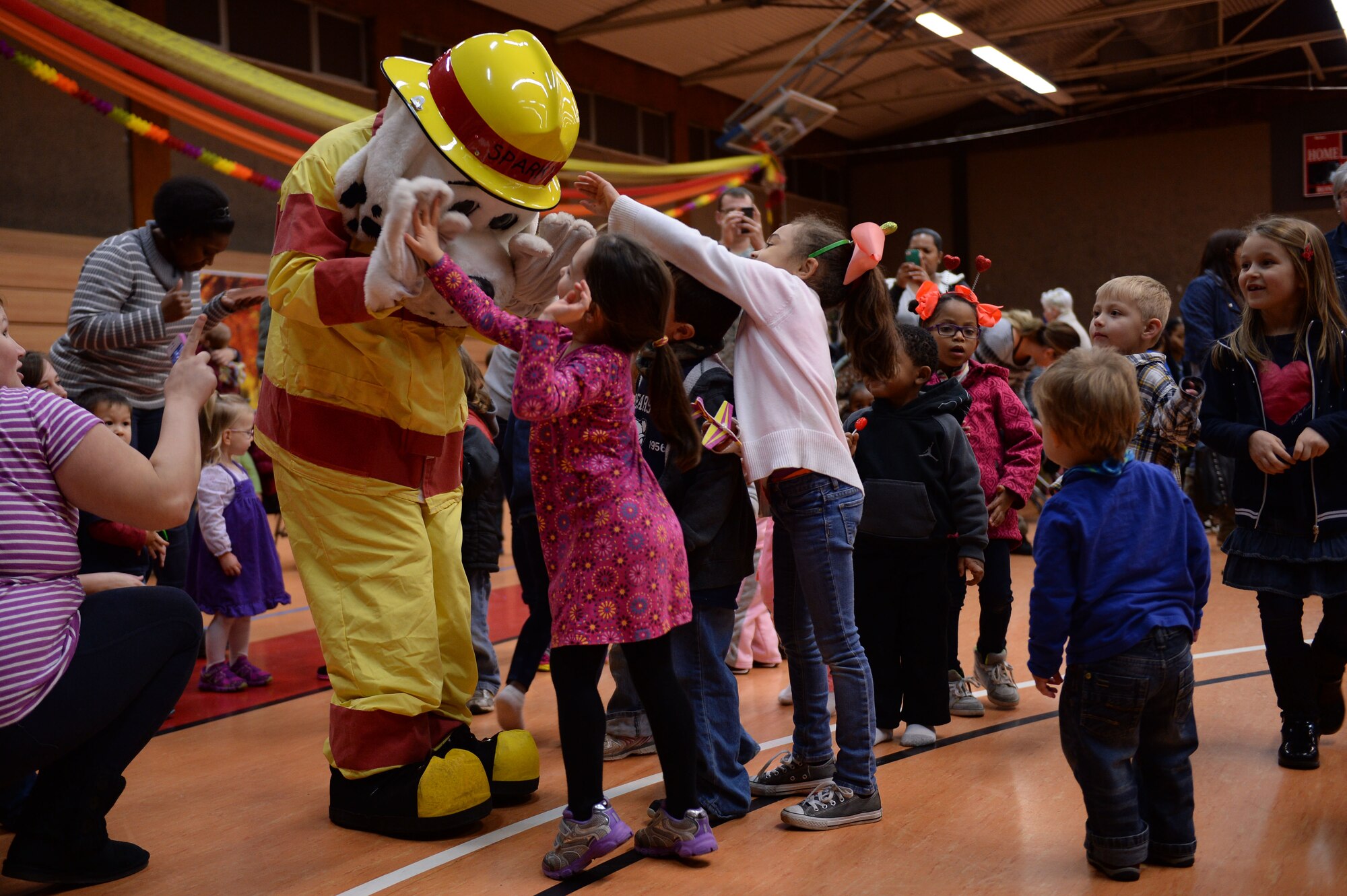 A U.S. Air Force Airman from the 52nd Civil Engineer Squadron fire department dressed as Sparky the Fire Dog high-fives a child during the Spangtacular Family Fall Festival Nov. 21, 2014, in the Skelton Memorial Fitness Center at Spangdahlem Air Base, Germany. Sparky the Fire Dog is the official mascot of the National Fire Protection Agency and made an appearance to interact with the children at the event. (U.S. Air Force photo by Staff Sgt. Daryl Knee/Released)