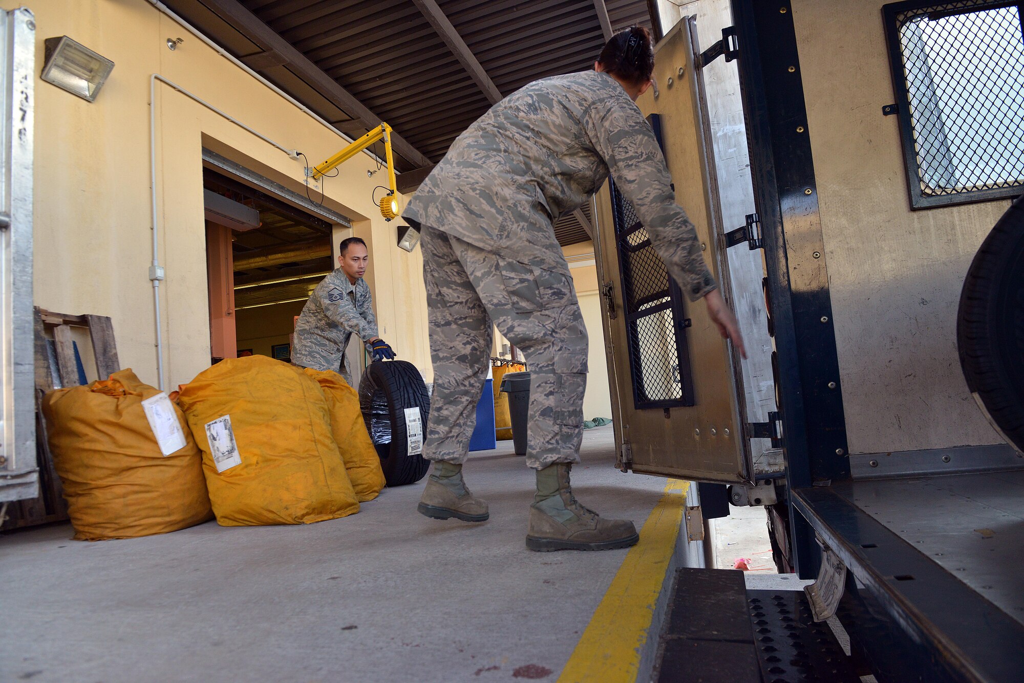 Master Sgt. Robert Onganco, 31st Communications Squadron post master, and Senior Airman Andrea Tassi, 31 CS postal clerk, load a delivery truck with tires, Nov. 25, 2014, at Aviano Air Base, Italy. During the holiday season, volunteer postal workers are needed to ensure on-time delivery. Volunteers can expect to sort, pitch, process and hand out parcels to customers after an initial orientation briefing. To volunteer this season, U.S. citizens can sign up in person or on the 31 CS SharePoint website. (U.S. Air Force photo/Airman 1st Class Ryan Conroy) 