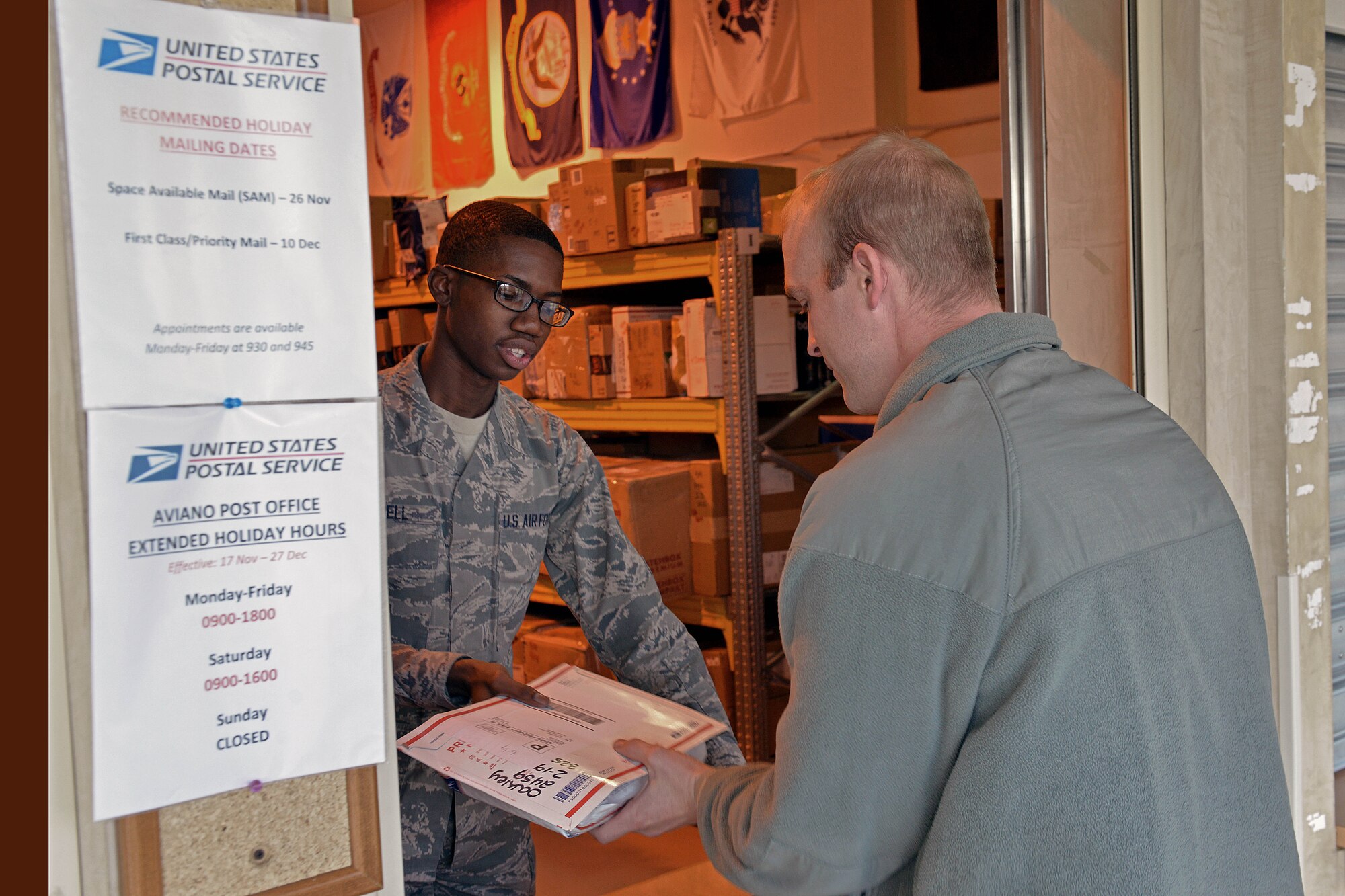 Airman 1st Class Kenneth Bell, 31st Communications Squadron postal clerk, hands a piece of mail to Staff Sgt. Paul Oakey, 31st Aircraft Maintenance Squadron crew chief, Nov. 25, 2014, at Aviano Air Base, Italy. During the holiday season, the post office receives approximately 60 percent more parcels. To help alleviate customer stress, the post office has extended it hours until Dec. 27 to 9 a.m. to 6 p.m., Monday through Friday.  (U.S. Air Force photo/Airman 1st Class Ryan Conroy)