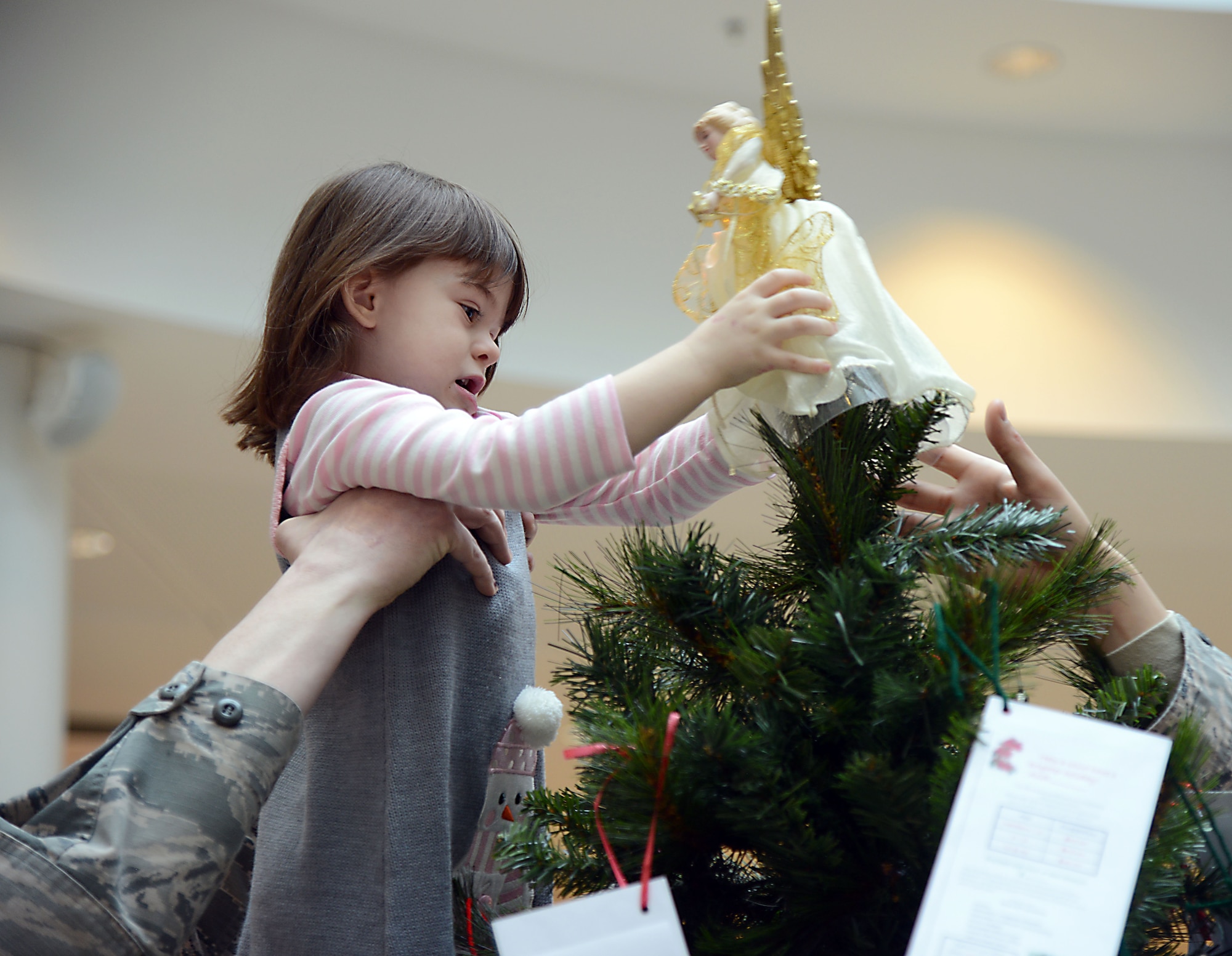 Master Sgt. Timothy Bliefnick, 86th Comptroller Squadron and Wing Staff Agencies first sergeant, helps his daughter, Annabella, place an angel decoration on top of a tree in the Kaiserslautern Military Community Center at Ramstein Air Base, Germany, Nov. 17, 2014. Thirteen trees are set up around the Kaiserslautern Military Community area to accept donations, meant to be used to provide financial relief to military families during the holiday season. (U.S. Air Force photo/Senior Airman Timothy Moore)