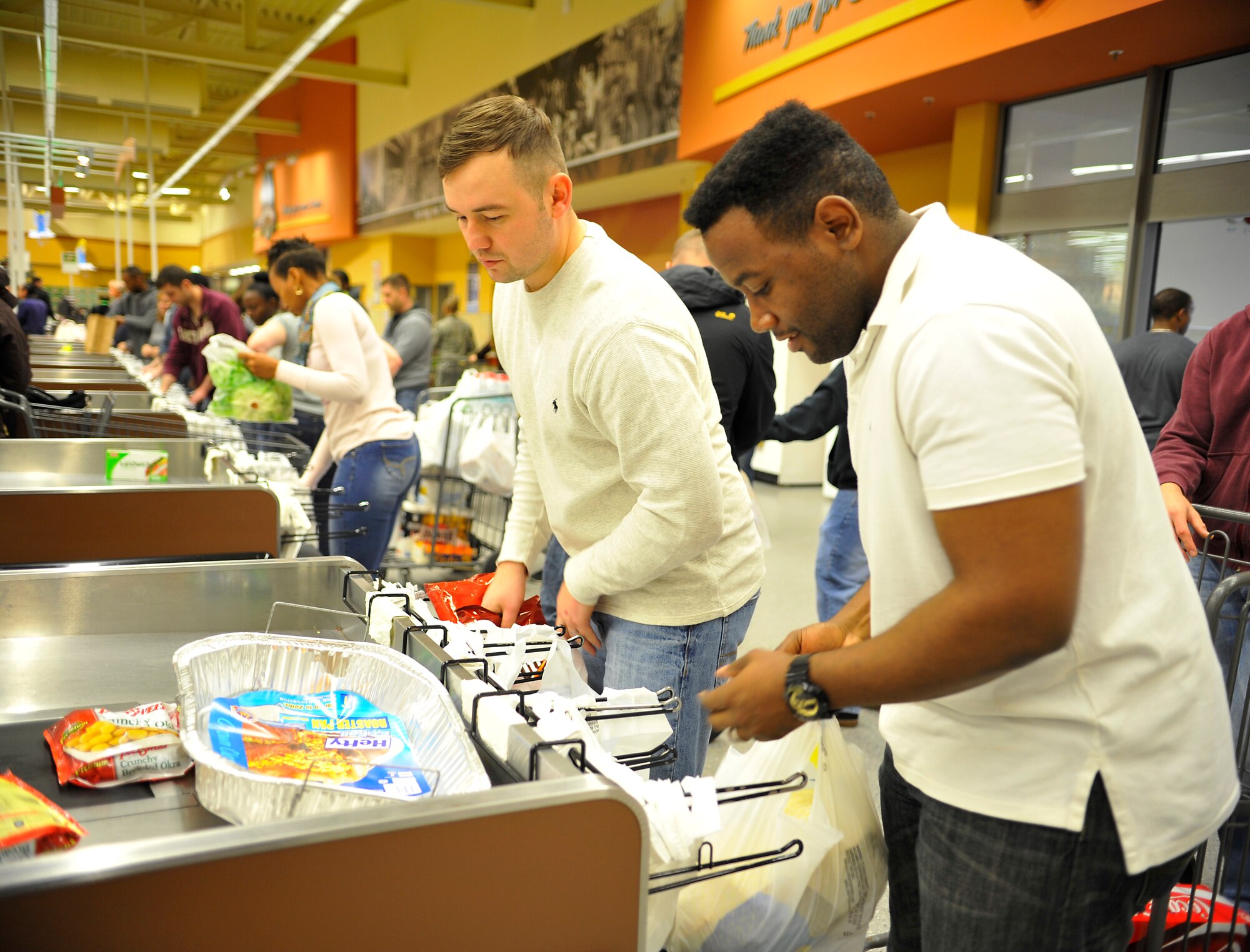 Senior Airman Andrey Antonyuk, 603rd Air and Space Communications Squadron RF transmissions technician, and Senior Airman Jeremy Walkes, 86th Communications Squadron Special Missions Flight Satellite Communications technician, bag a customer’s groceries during a two-day commissary bagging event for Operation Warmheart Nov. 23, 2014 at Ramstein Air Base, Germany. Operation Warmheart consists of two voluntary events, commissary bagging and the “Ring A Bell” campaign, to raise money going to Airmen and families in need during the holiday season. (U.S. Air Force photo/Airman 1st Class Larissa Greatwood)