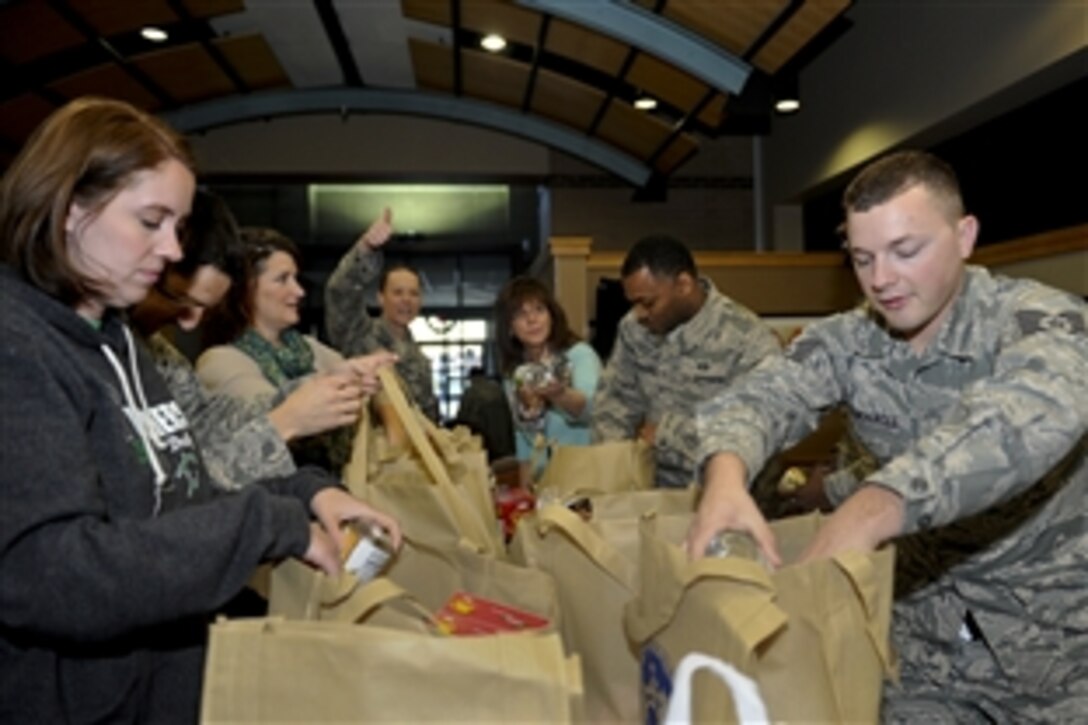 Airmen, family and friends place donated food items in bags on McConnell Air Force Base, Kan., Nov. 25, 2014. Volunteers assembled about 200 Thanksgiving baskets and first sergeants delivered them to airmen in need of a helping hand.