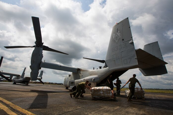 U.S. Marines and Sailors with SPMAGTF Crisis Response - Africa prepare to load bags of concrete onto an MV-22B Osprey to help local and international health organizations build Ebola Treatment Units while in support of Operation United Assistance in Monrovia, Liberia, Nov. 21, 2014. United Assistance is a Department of Defense operation to provide command and control, logistics, training, and engineering support to U.S. Agency for International Development- led efforts to contain the Ebola virus outbreak in West African nations. (U.S. Marine Corps photo by Lance Cpl. Andre Dakis/SPMAGTF-CR-AF Combat Camera/Released)